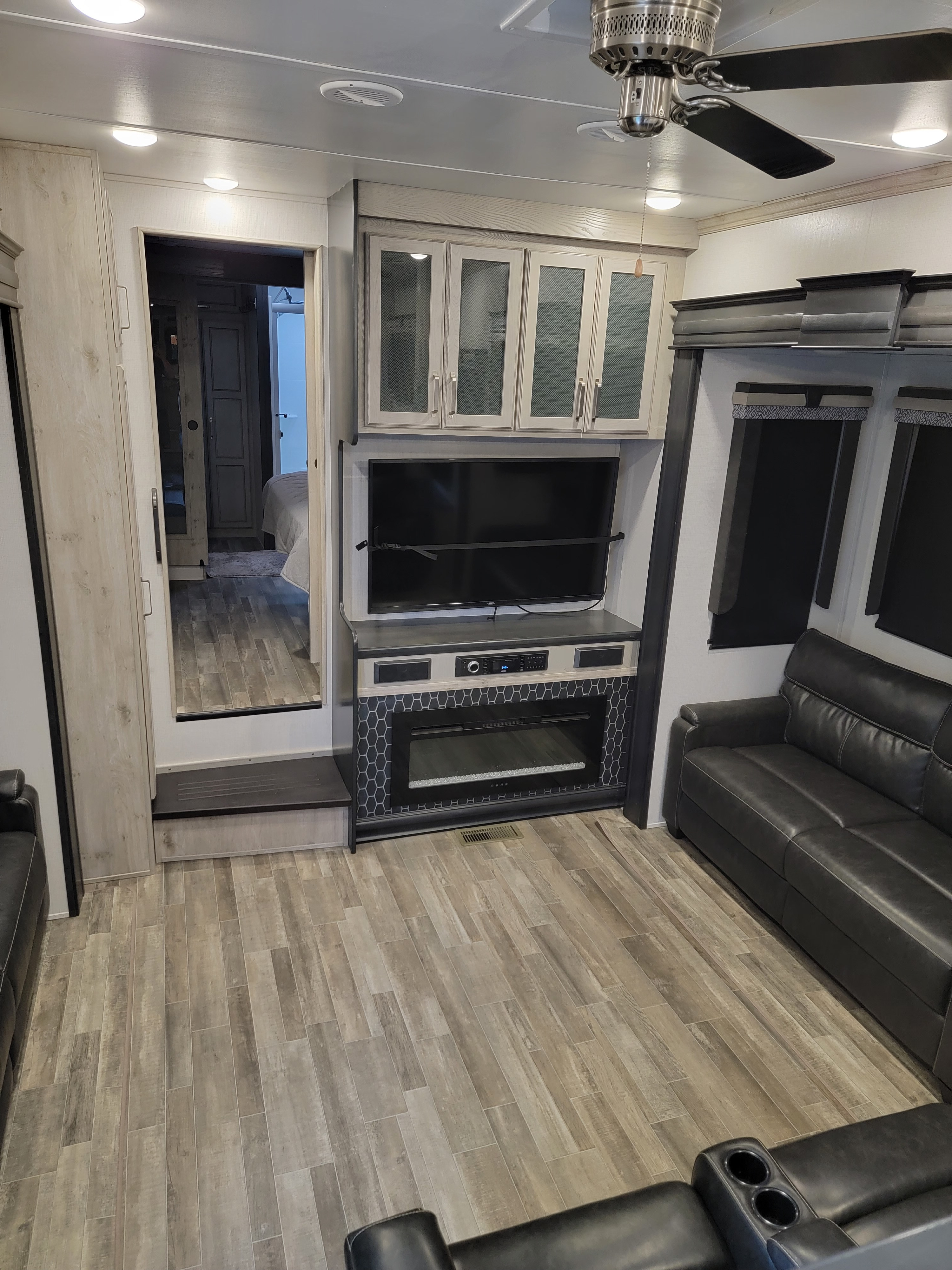 Modern RV rental living room with fireplace, TV, and comfortable seating. Bedroom visible through doorway.. Keystone RV Alpine 2021