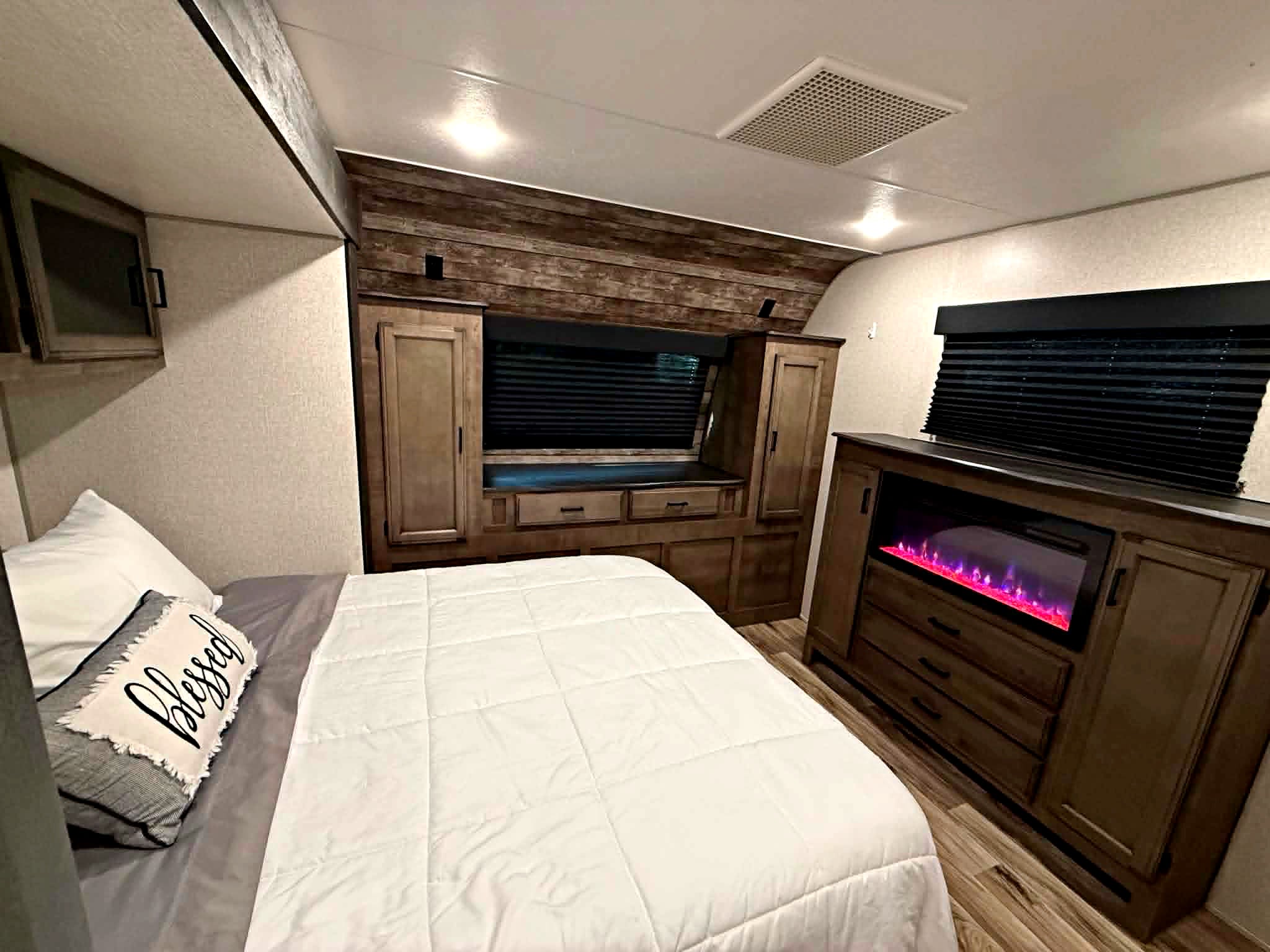 This cozy RV rental bedroom features a comfy bed, warm fireplace, and ample storage, ideal for your next adventure.. Venture Other 2022