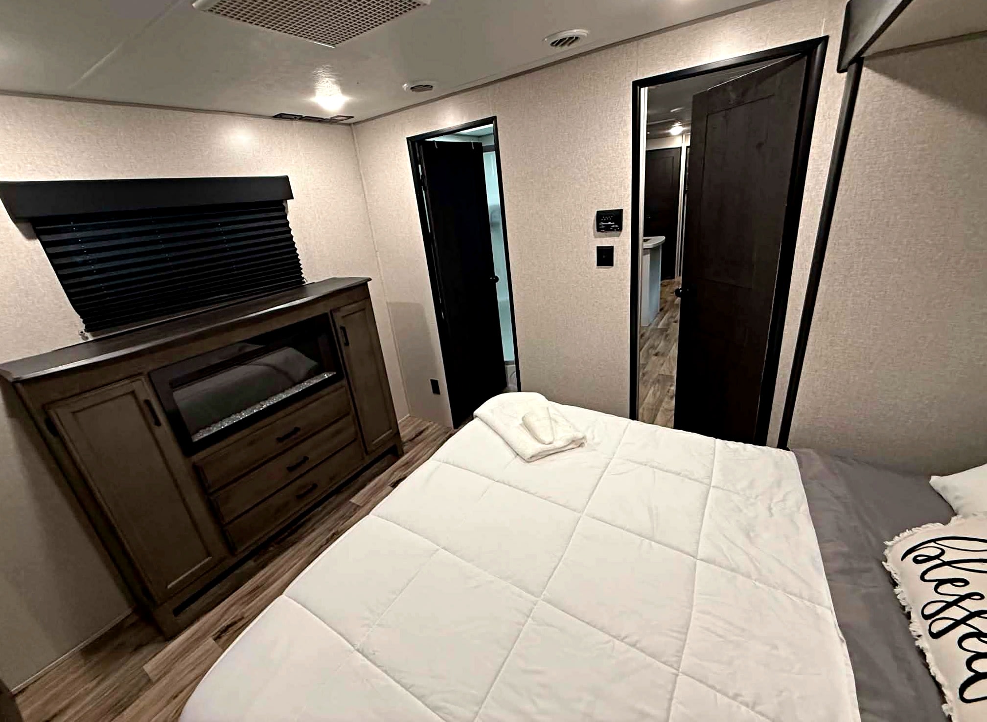 Inviting RV rental bedroom with a comfy bed, "blessed" pillow, wood dresser, and dark doors, offering cozy travel.. Venture Other 2022