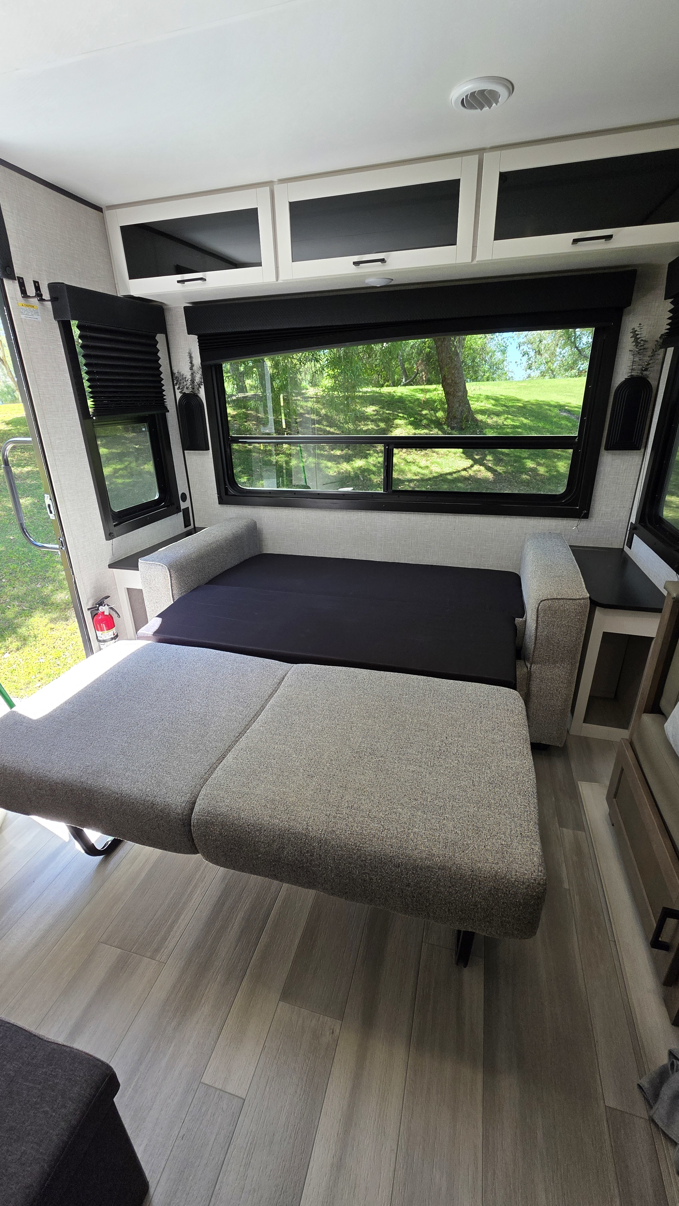 RV rental travel trailer interior: a versatile convertible sofa bed, overhead storage, and bright scenic window views.. Go Play 26RLS 2025