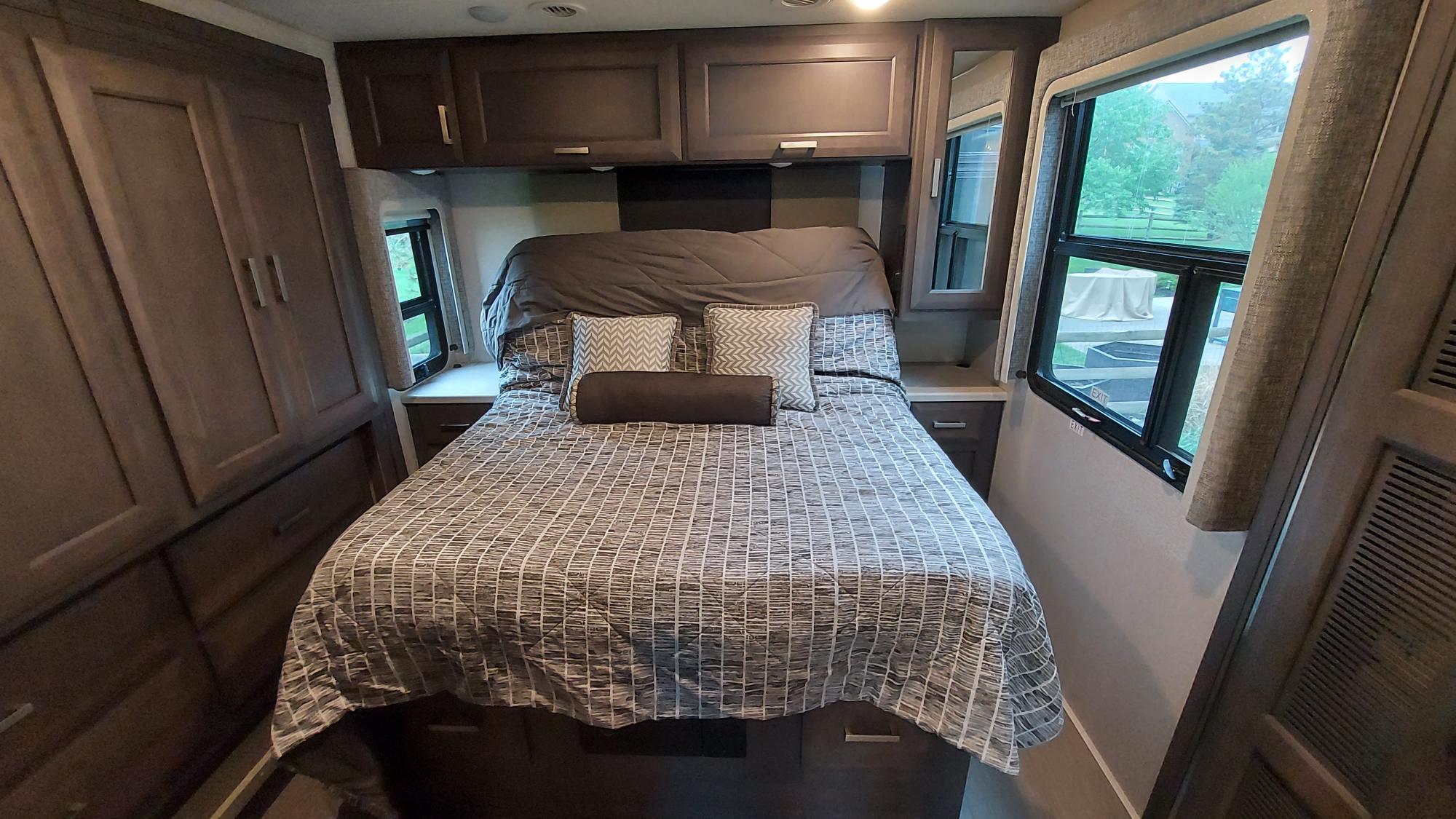 Cozy RV rental bedroom with a comfy bed, overhead storage, and large windows. Perfect for your next adventure!. Thor Palazzo 2023
