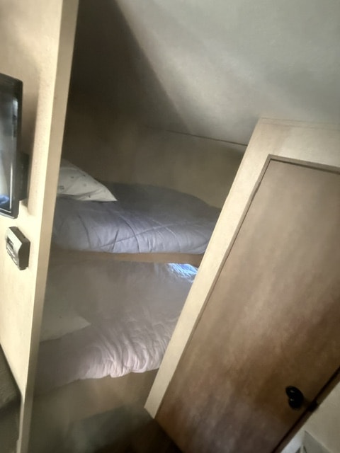 Cozy bunk beds inside an RV rental. This compact sleeping area includes a TV to the left and a closed door on the right.. Starcraft Autumn Ridge Outfitter 2018