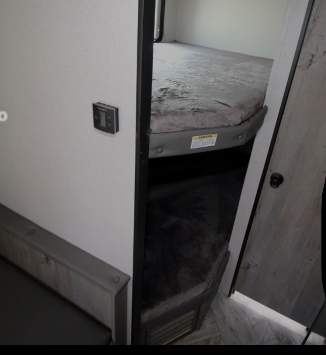 RV rental interior: two bunk beds with gray bedding, a wall thermostat, and a seating area.. Keystone RV Springdale 2022