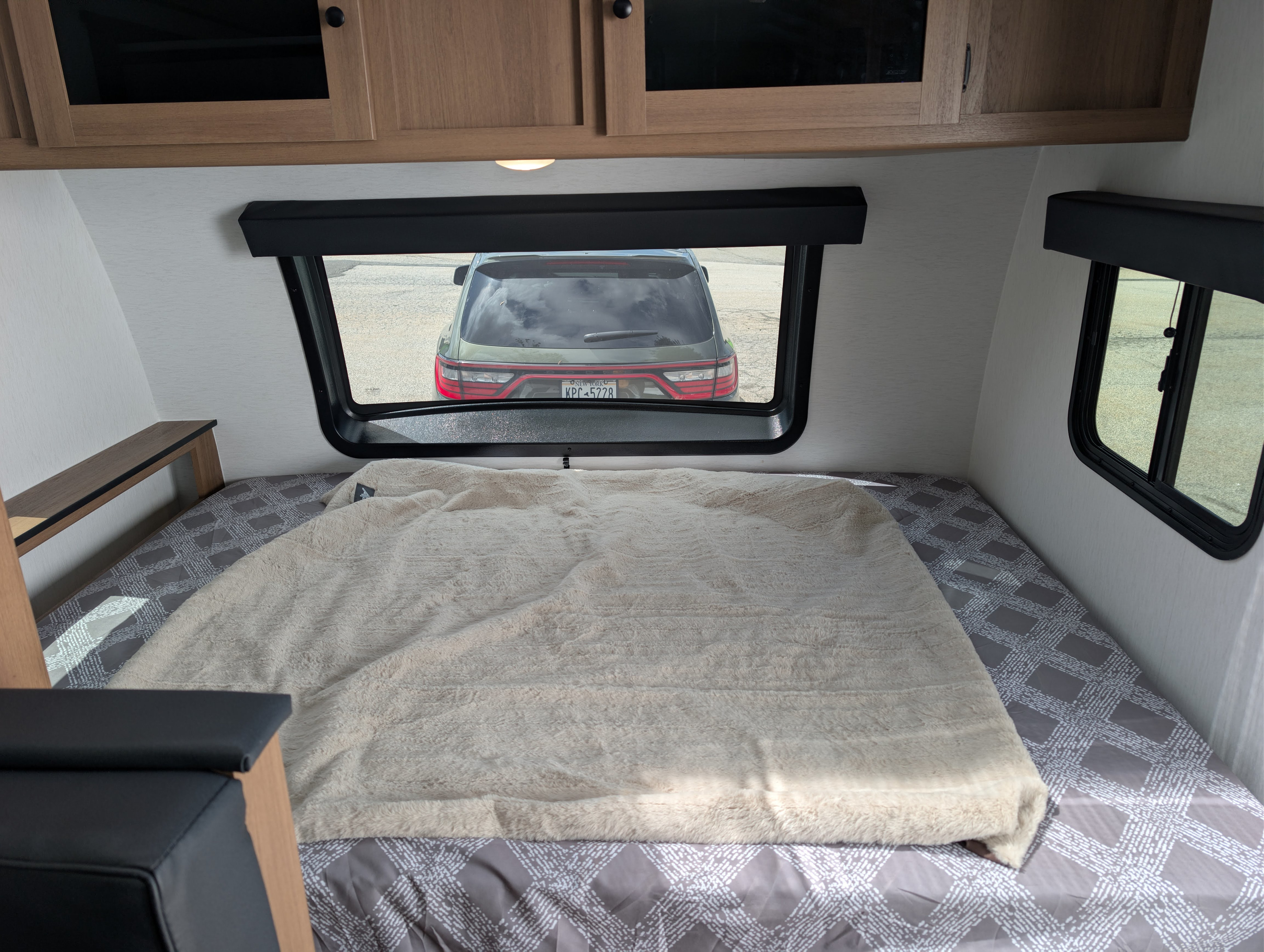 Cozy RV rental bedroom featuring a bed with a soft blanket, storage cabinets, and a clear view out the window.. Forest River Apex Nano 194 BHS 2026