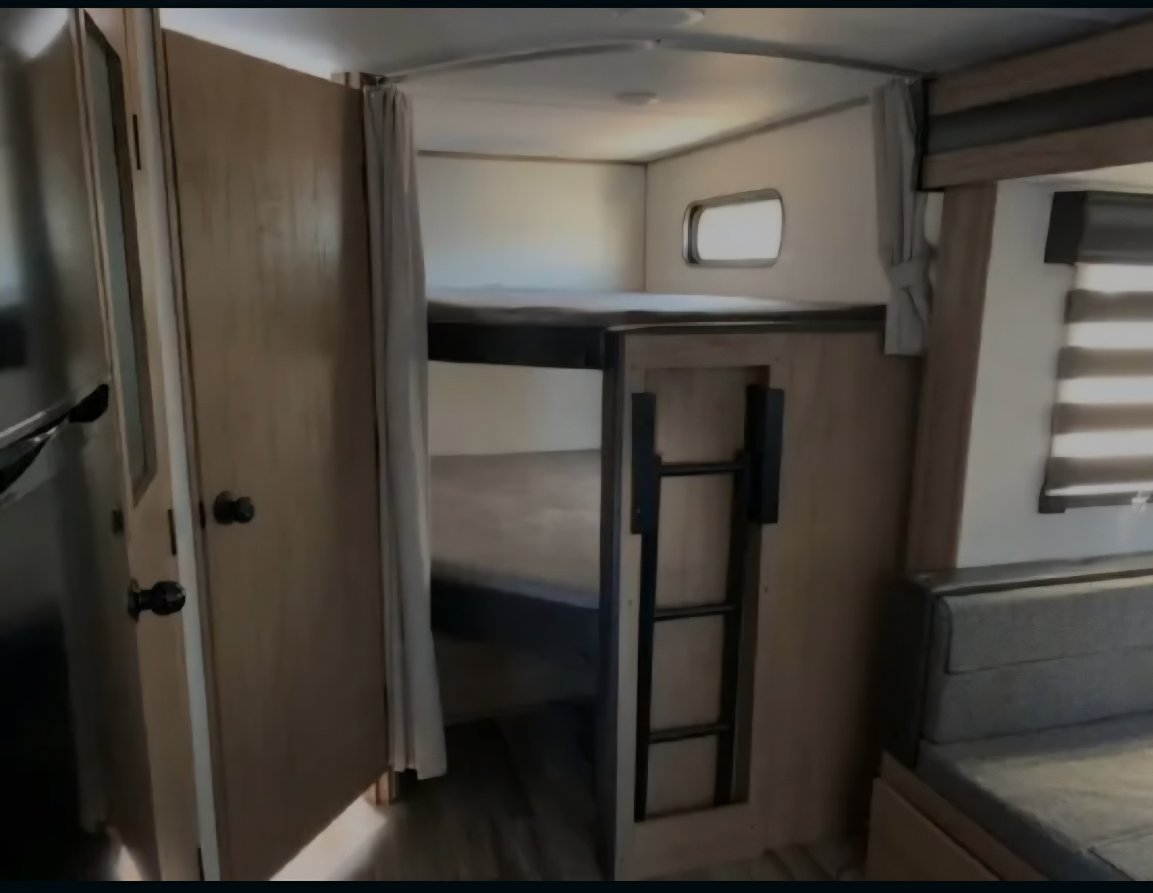 An RV rental interior featuring comfortable bunk beds with a ladder, a small window, and a soft-cushioned dinette.. Forest River Cherokee Alpha Wolf 2023