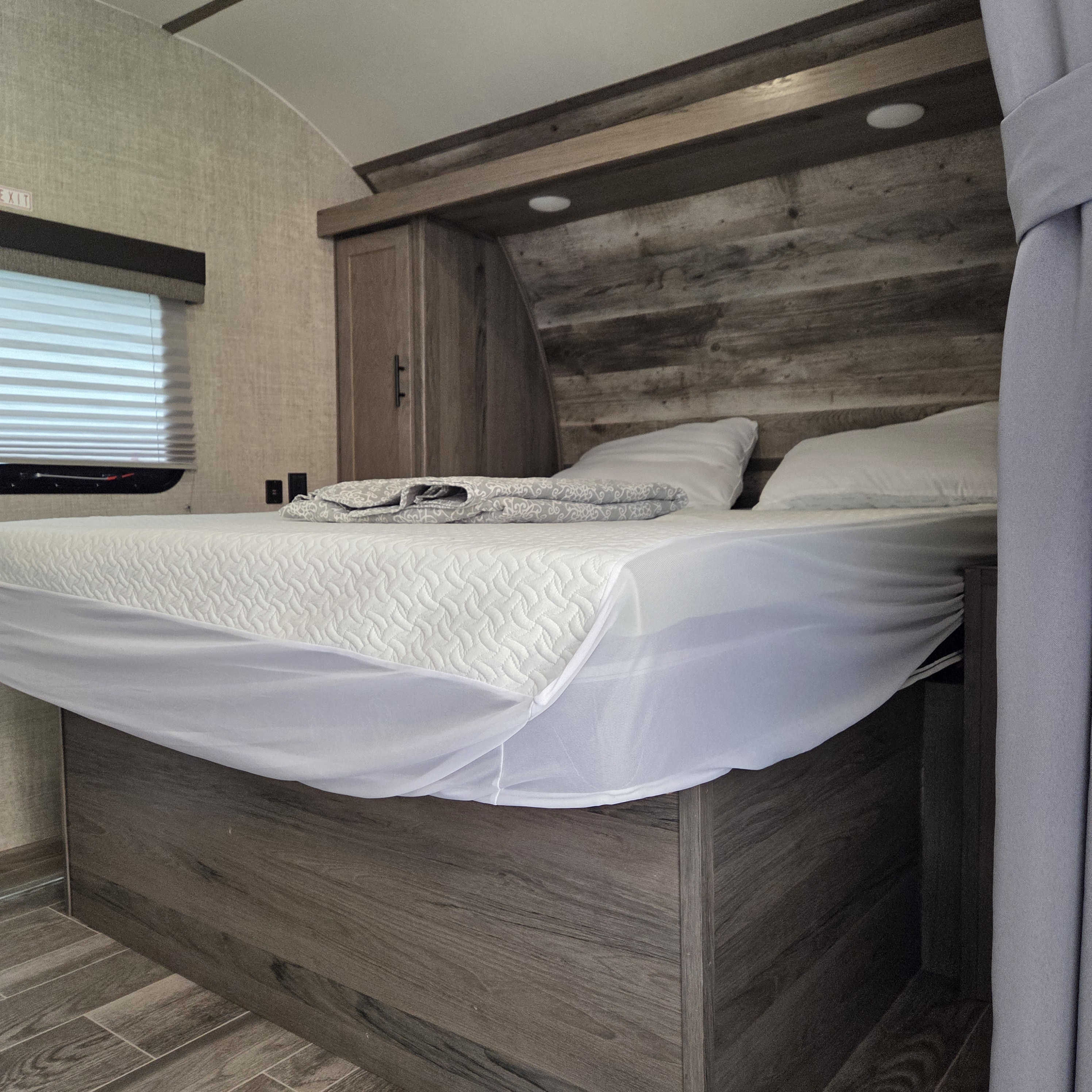 RV rental bedroom: Modern design with a bed, white mattress protector, wood headboard, cabinets, and window blinds.. Gulf Stream Enlighten 2021