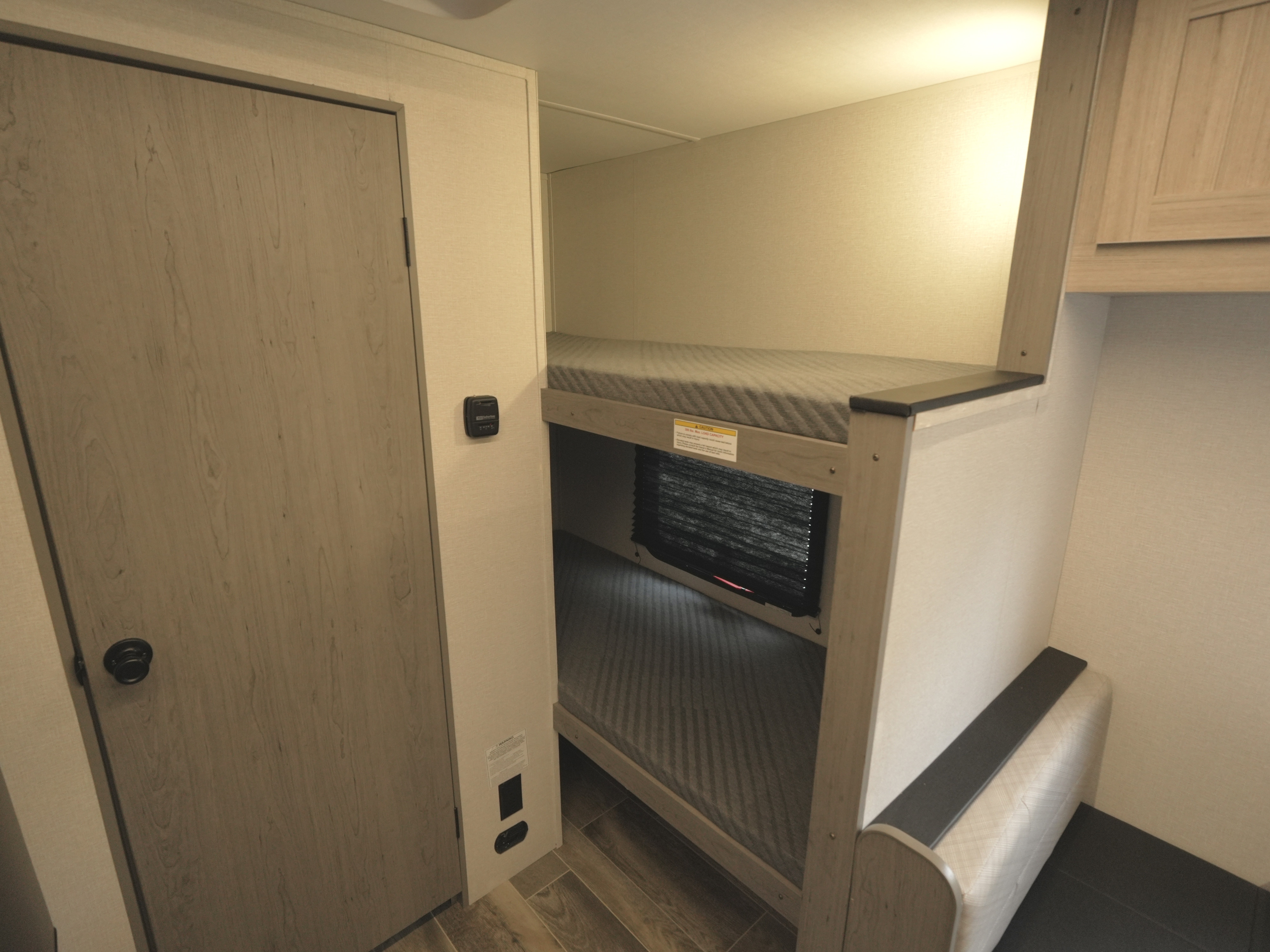 Cozy bunk beds in an RV rental, featuring a privacy shade, door, and thermostat. Ideal for family sleeping in a camper.. Heartland RVs Mallard 2025