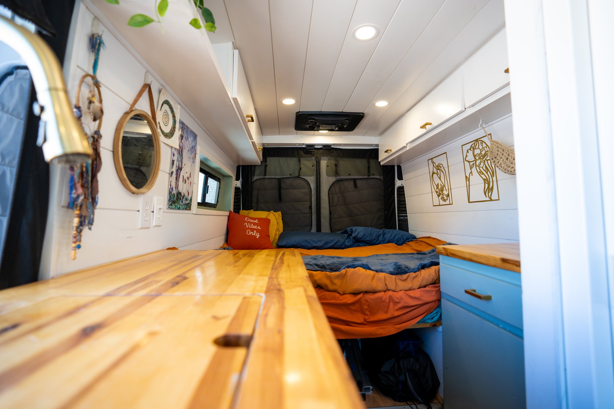 Cozy rv rental interior with a bed, wooden counter, and decor. Ideal for van life adventures.. Dodge Ram Promaster 2500 2022