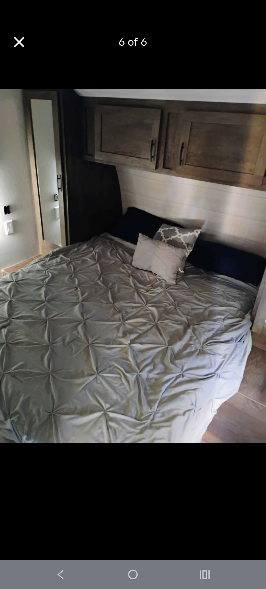 RV rental master bedroom with grey comforter, accent pillows, and overhead wood cabinets.. Forest River EVO T2850 2022
