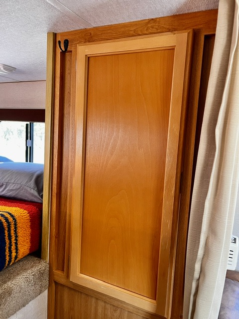 RV rental interior featuring a wooden cabinet door with a storage hook, offering practical storage solutions next to a bed.. toyota tundra 2010