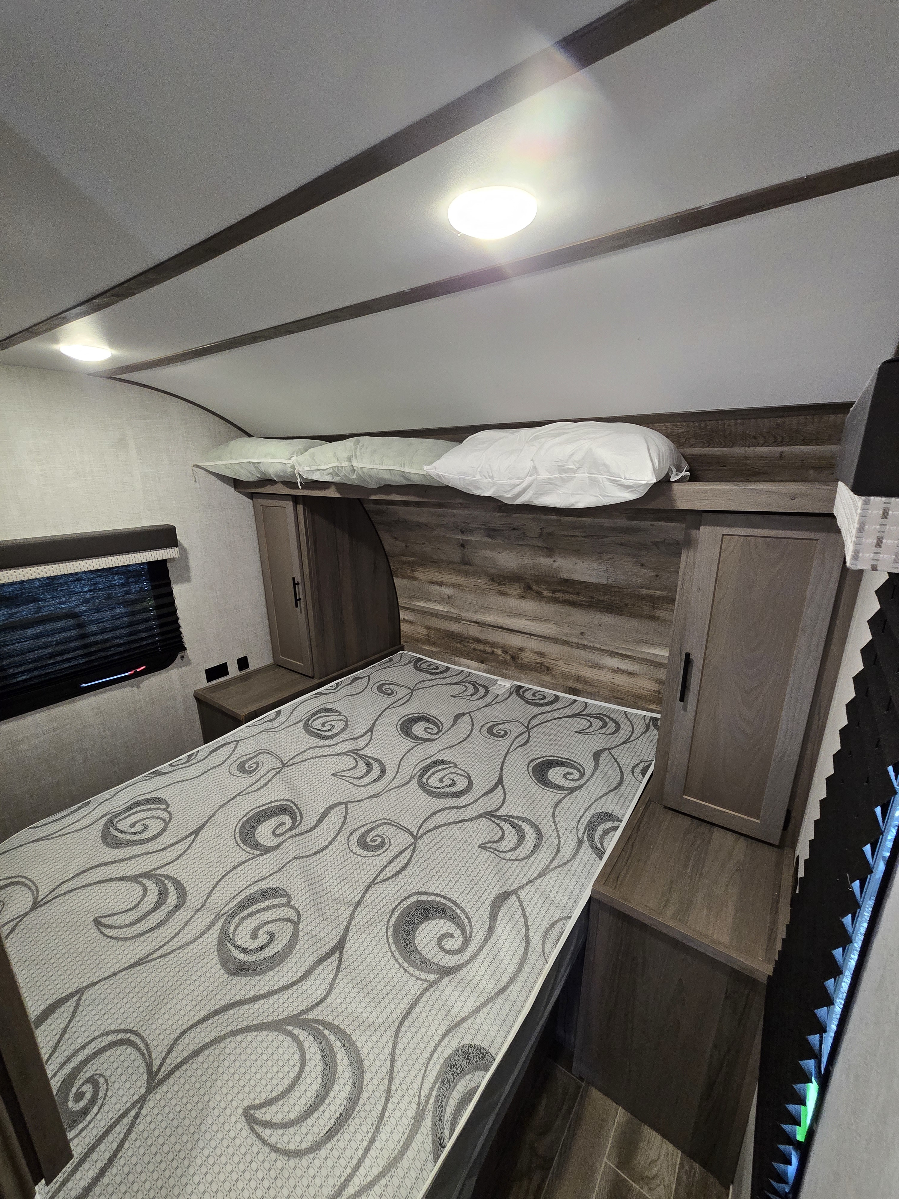 RV rental bedroom showing a patterned mattress, overhead storage for pillows, and built-in side cabinets. Ideal for travel comfort.. Gulf Stream Kingsport 2022