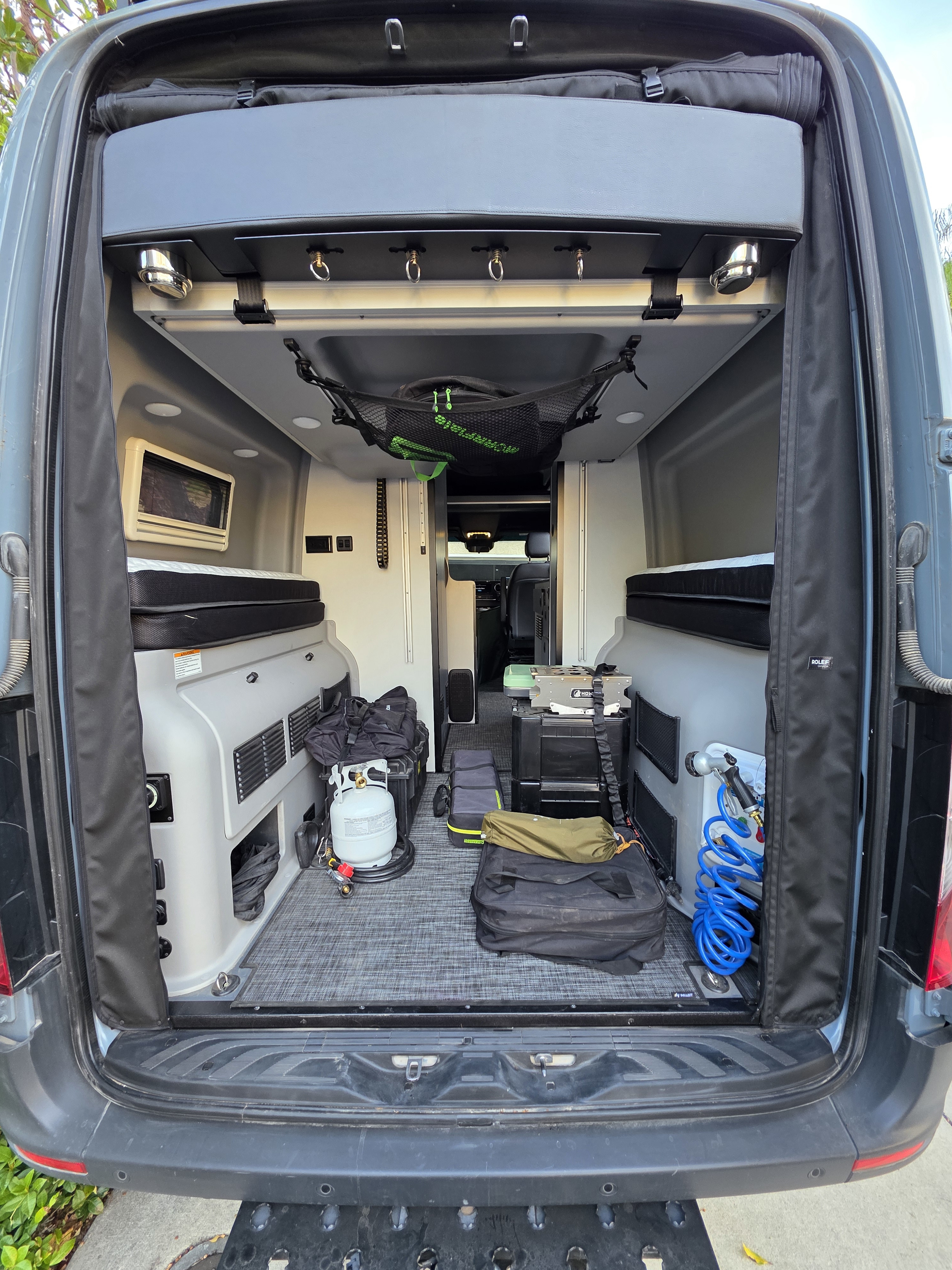 Packed RV rental camper van interior, featuring beds, camping stove, propane, and organized gear for trips.. Winnebago Revel 2022