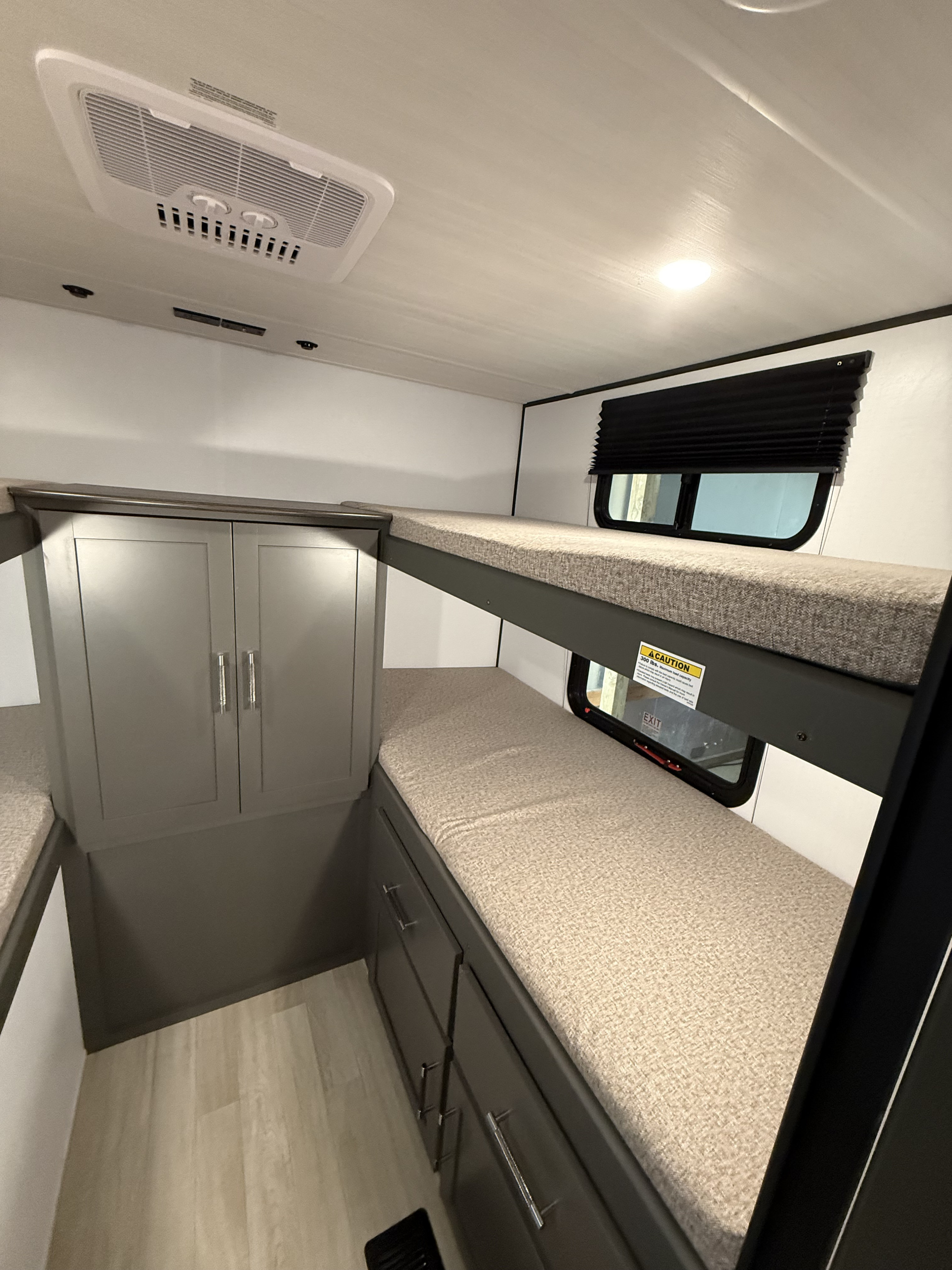 RV rental interior: bunk beds, cabinet storage, AC unit, and windows with blinds offer compact comfort for your adventure.. Keystone RV Bullet 2026