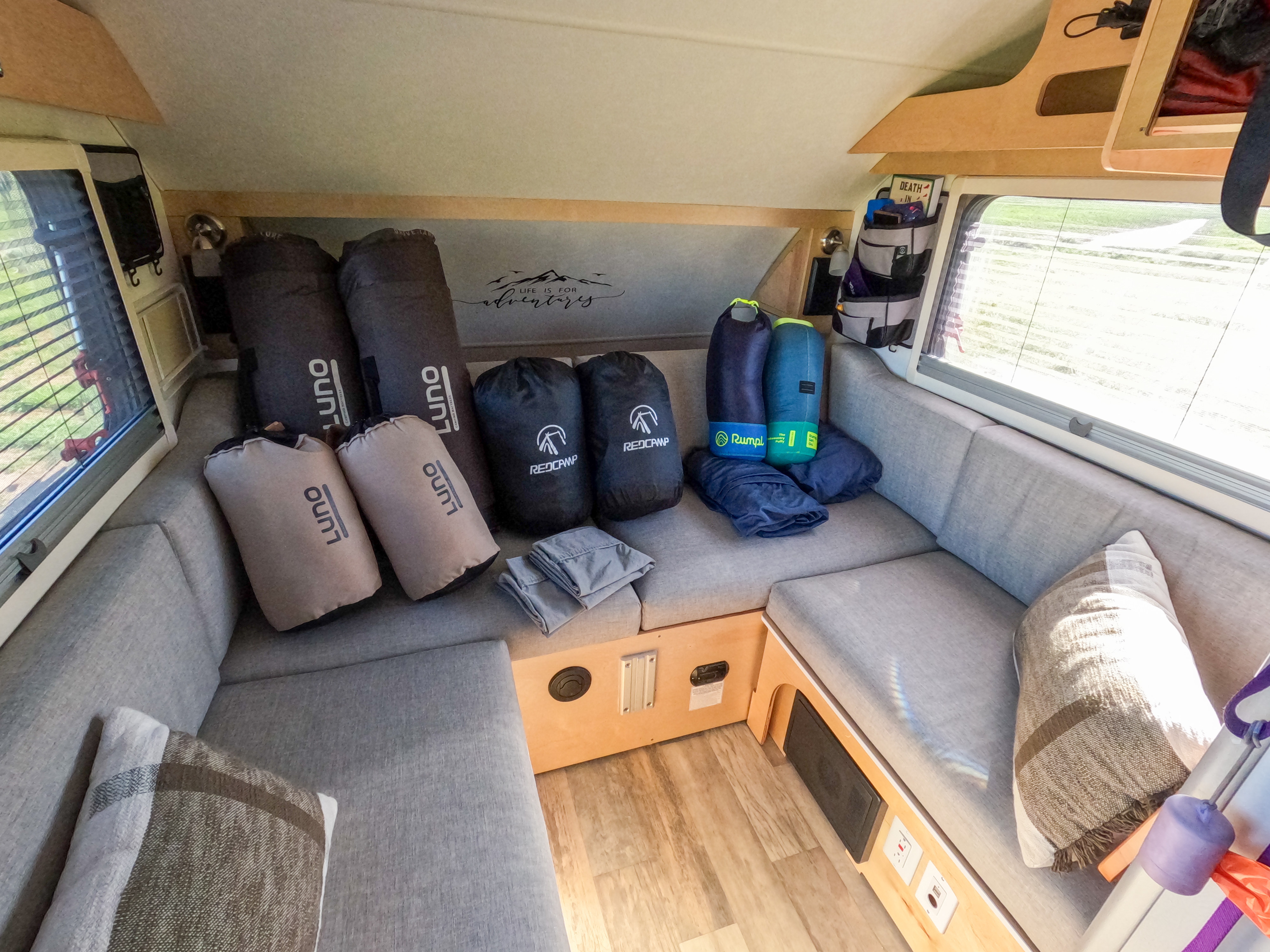 RV rental: Camper interior with grey upholstered seating, bundled Luno mattresses, Redcamp sleeping bags, & Rumpl blankets.. nuCamp T@B 2022