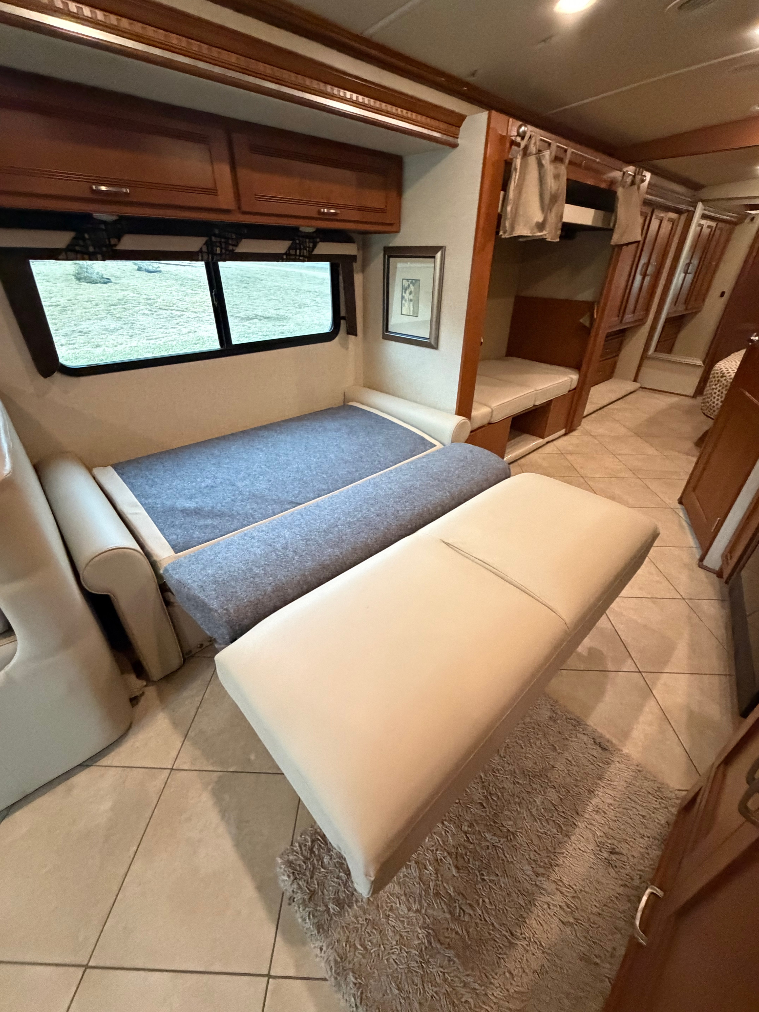 Cozy RV rental interior showing a convertible dinette bed, bunk beds, and wooden cabinets, perfect for family trips.. Winnebago Forza 2014