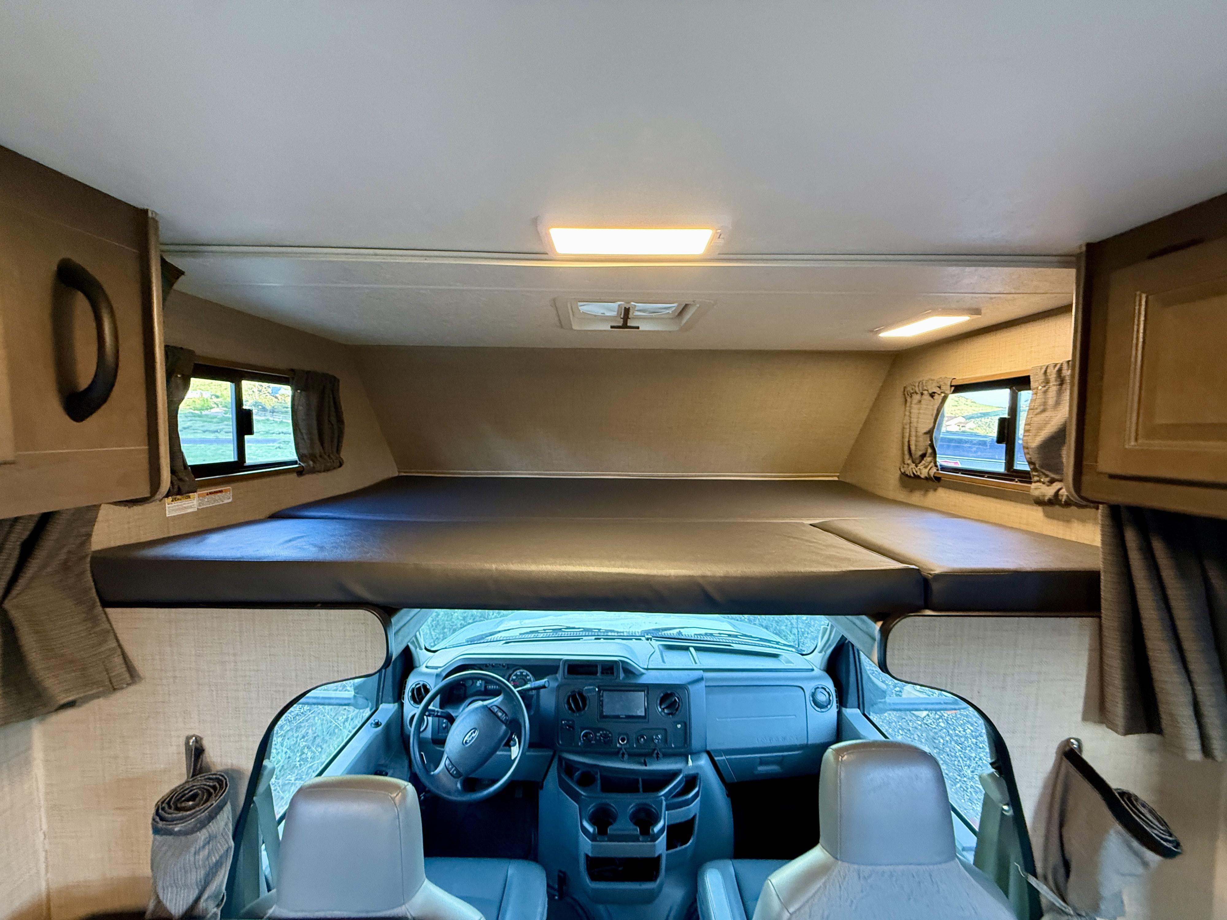 Inside an rv rental: View of the over-cab sleeping bunk, cockpit area, and windows, perfect for travel.. Thor Majestic 2020