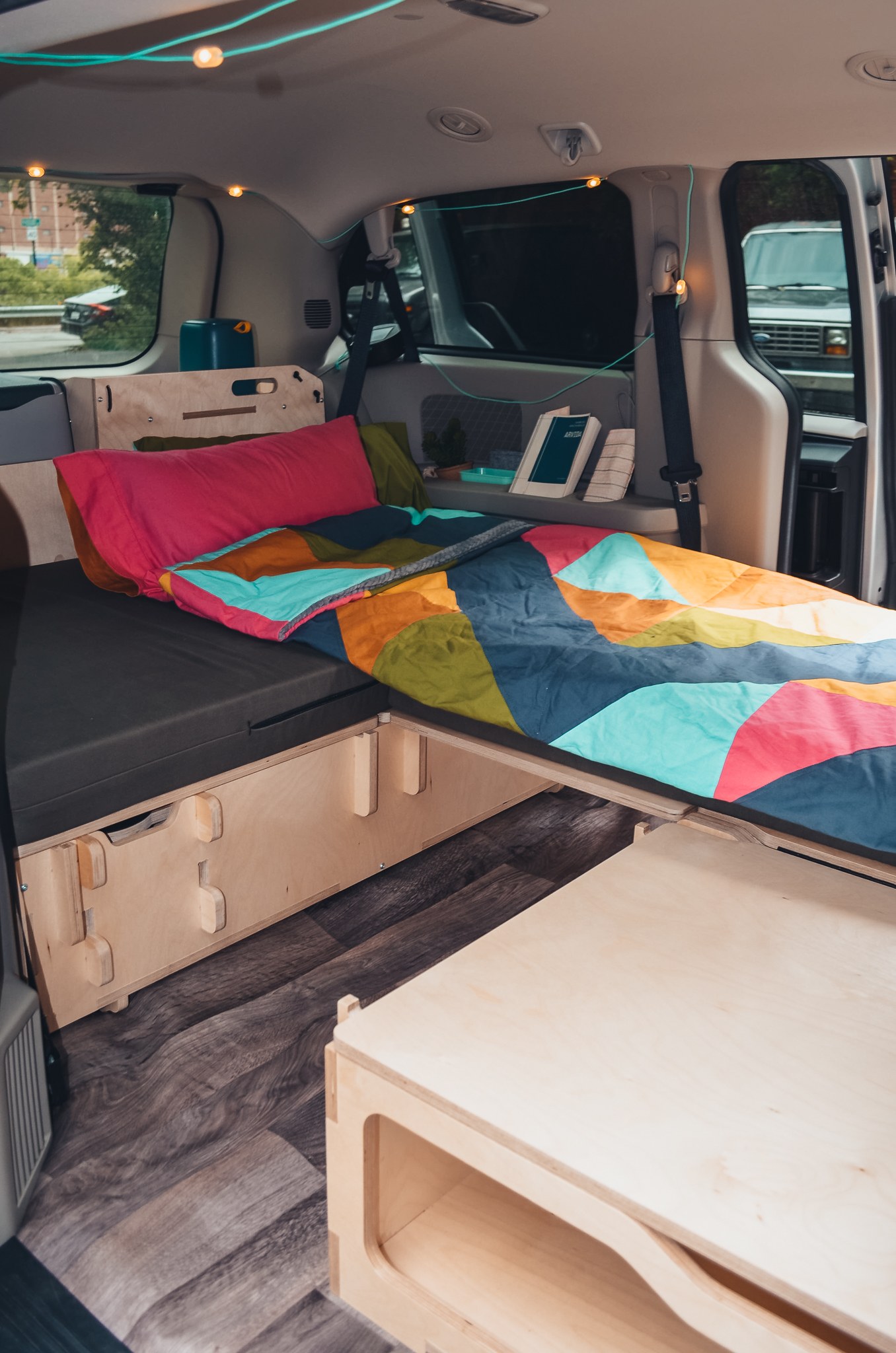 Inside a practical rv rental: a vibrant bed with wooden storage and ambient lights, designed for comfortable mobile living.. Chrysler 2025