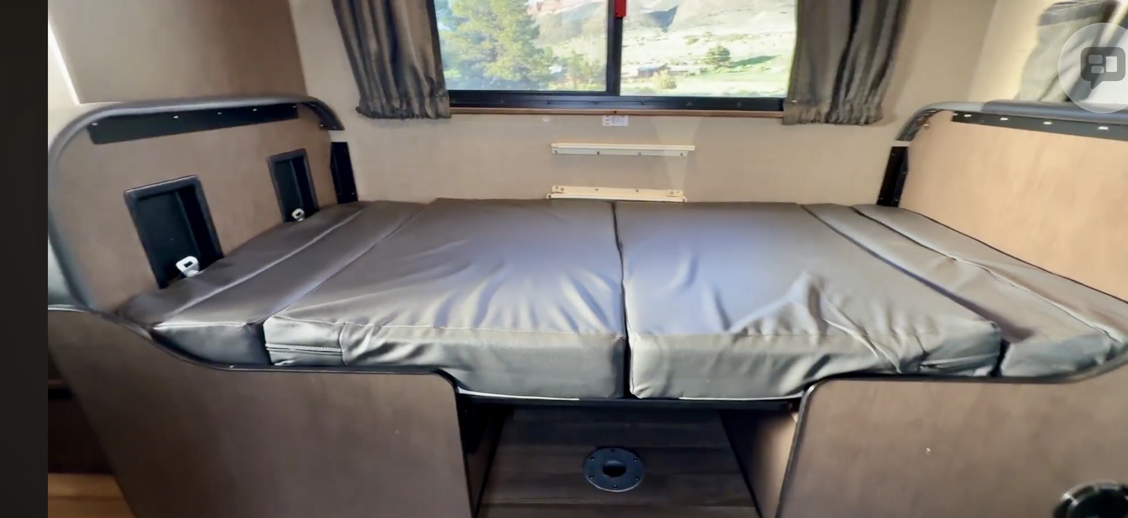RV rental's modular sleeping area with grey cushions, scenic window view, & side panel storage. Ready for your adventure.. Thor Majestic 2020