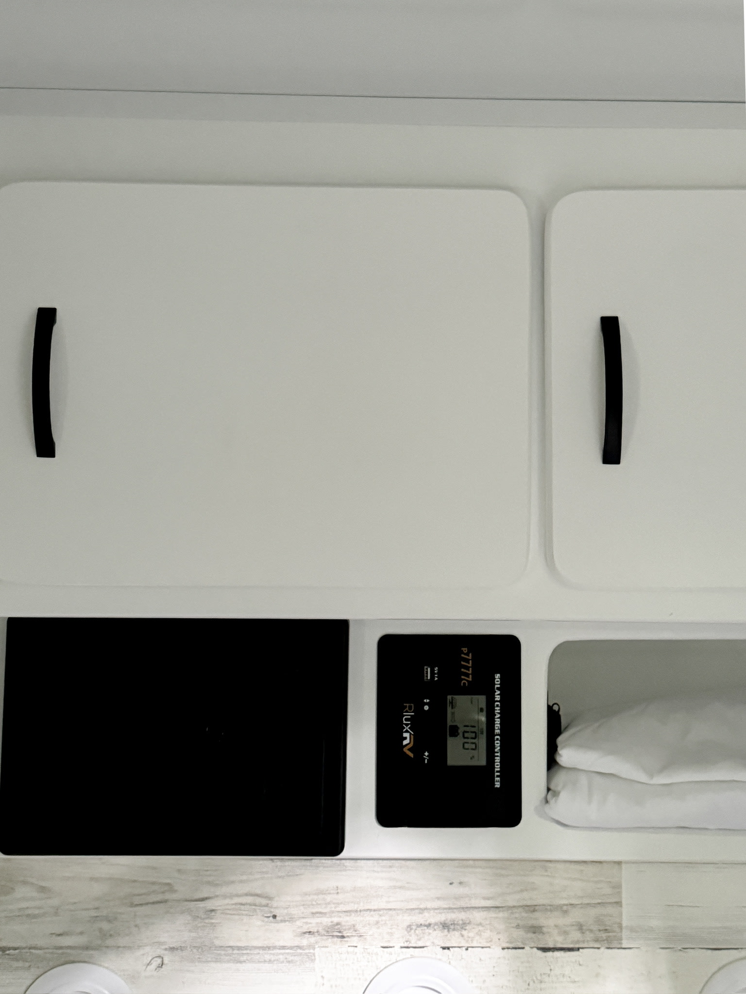 Inside an RV rental: storage cabinets, an RluxRV solar charge controller at 100%, and a compartment with folded items.. Modern Buggy RV CB12 2025