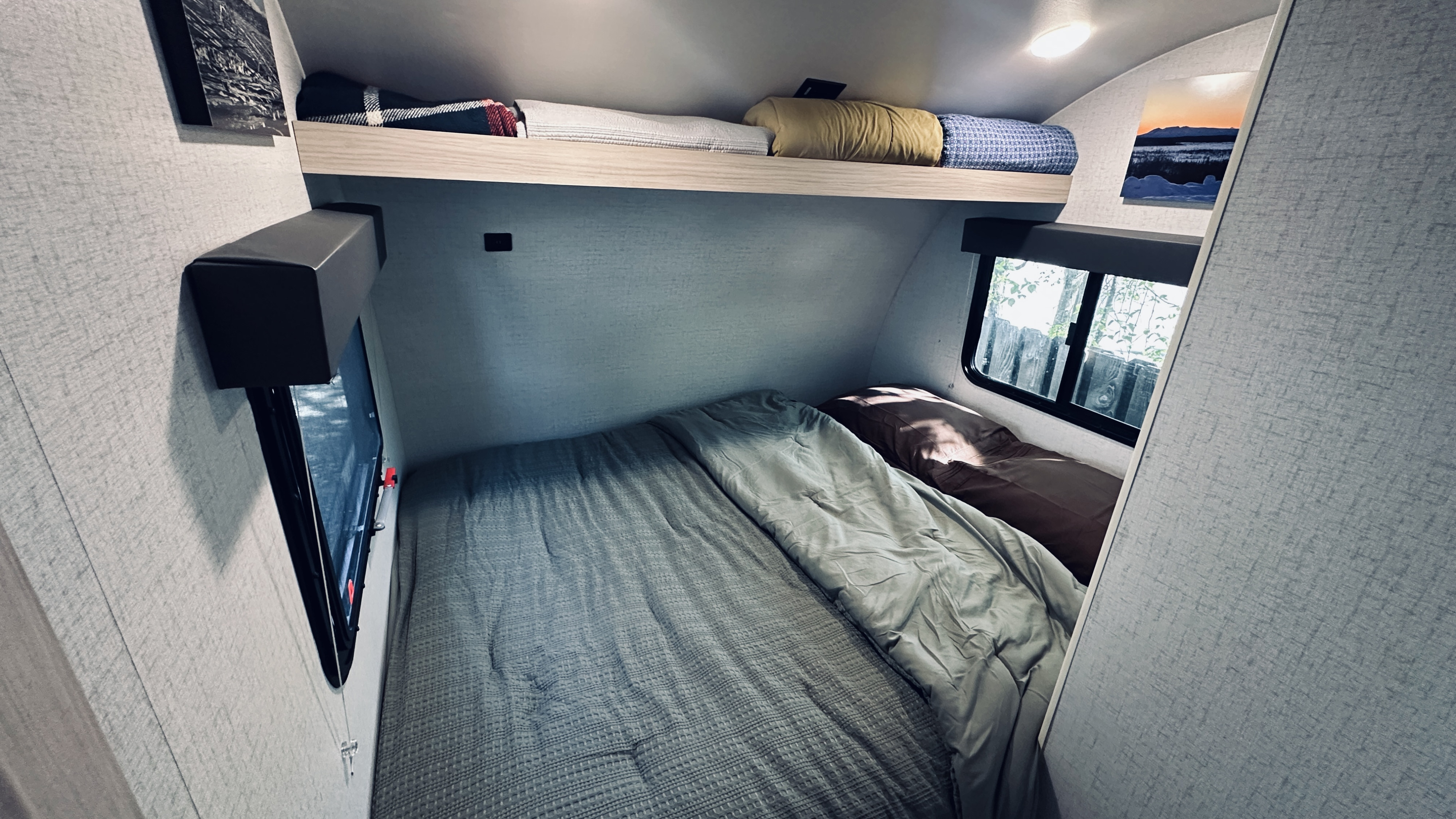Cozy RV rental sleeping area with a made bed, overhead shelf, and window views. Perfect for travel.. Winnebago Hike 2022