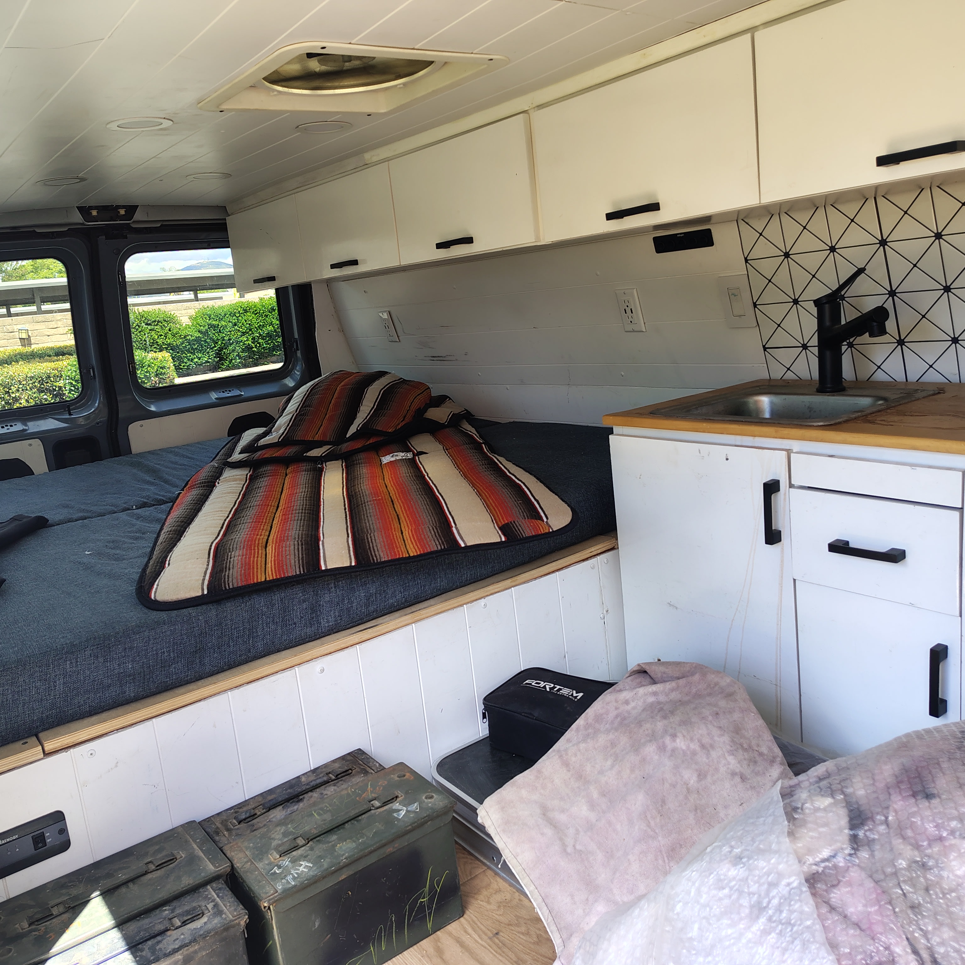 RV rental interior: cozy bed, small kitchen, overhead cabinets, and storage for mobile living adventures.. Ford Econoline E350 2001