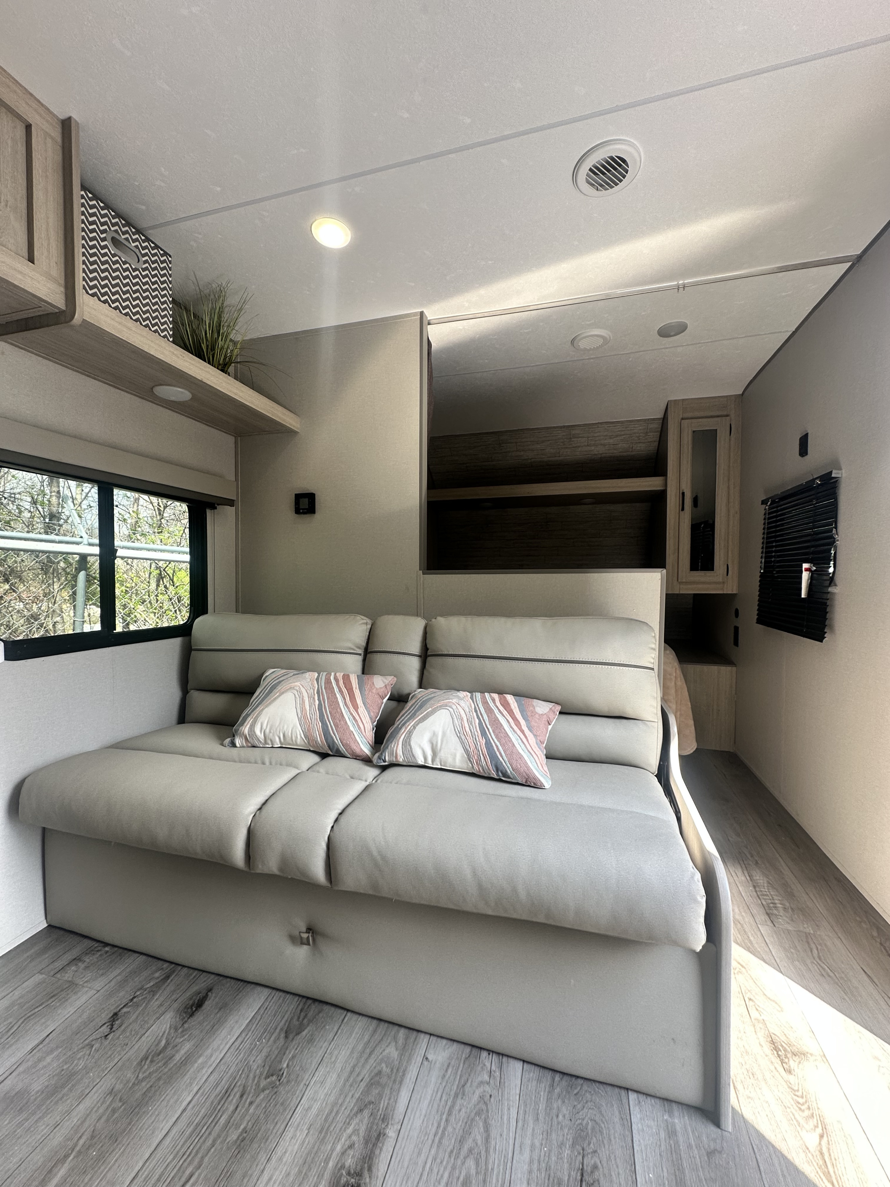 Experience comfort in this RV rental's living area, featuring a spacious light gray sofa, modern decor, and window.. Forest River Coachmen Catalina Summit 8 261 BH 2026