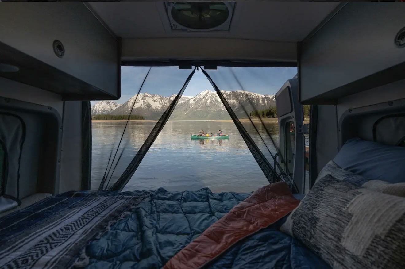 Wake up to stunning views from your RV rental! Cozy bed, tranquil lake, snow-capped mountains, and a family canoeing.. Winnebago Solis 59P National Park Fundation 2026