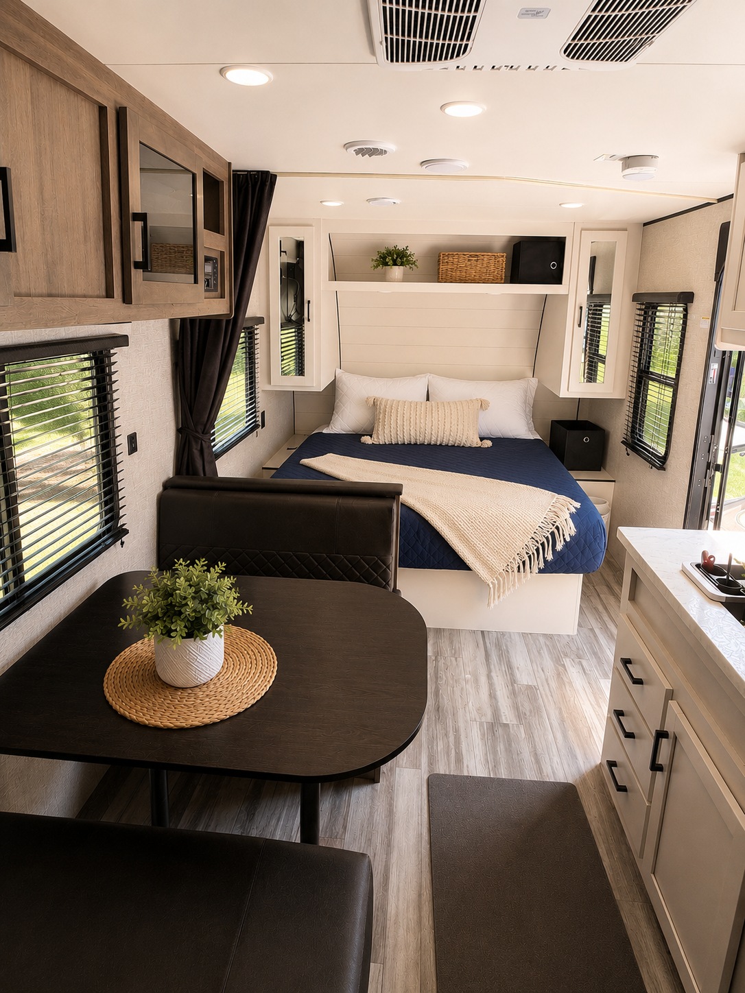 This modern RV rental interior features a cozy bedroom, dining booth, and compact kitchen, with light wood tones and ample light.. Jayco Jay Flight 2024