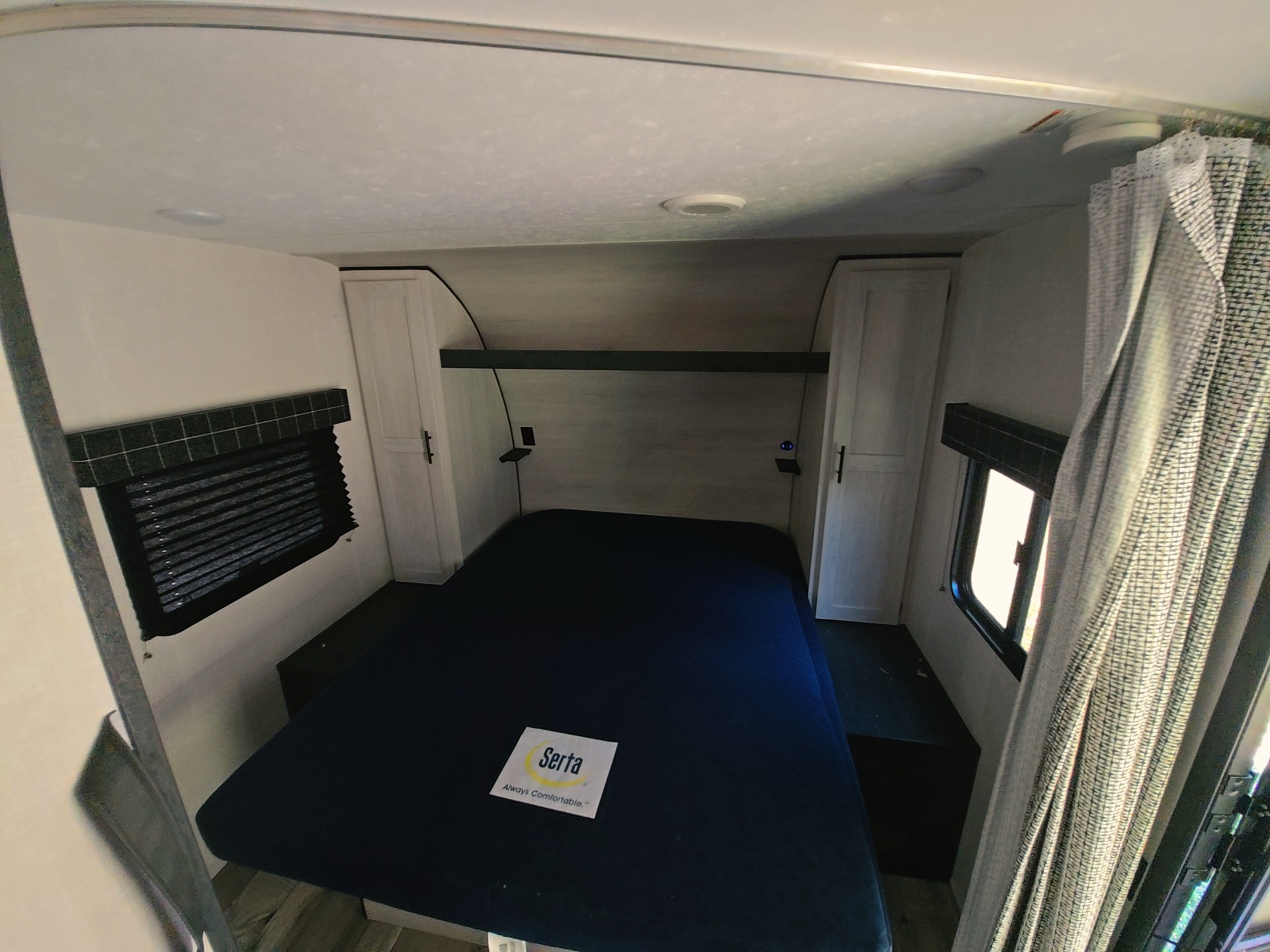 RV rental bedroom interior featuring a Serta bed, side cabinets, and windows with blinds, ideal for a comfortable stay.. KZ RV sportsman 2022