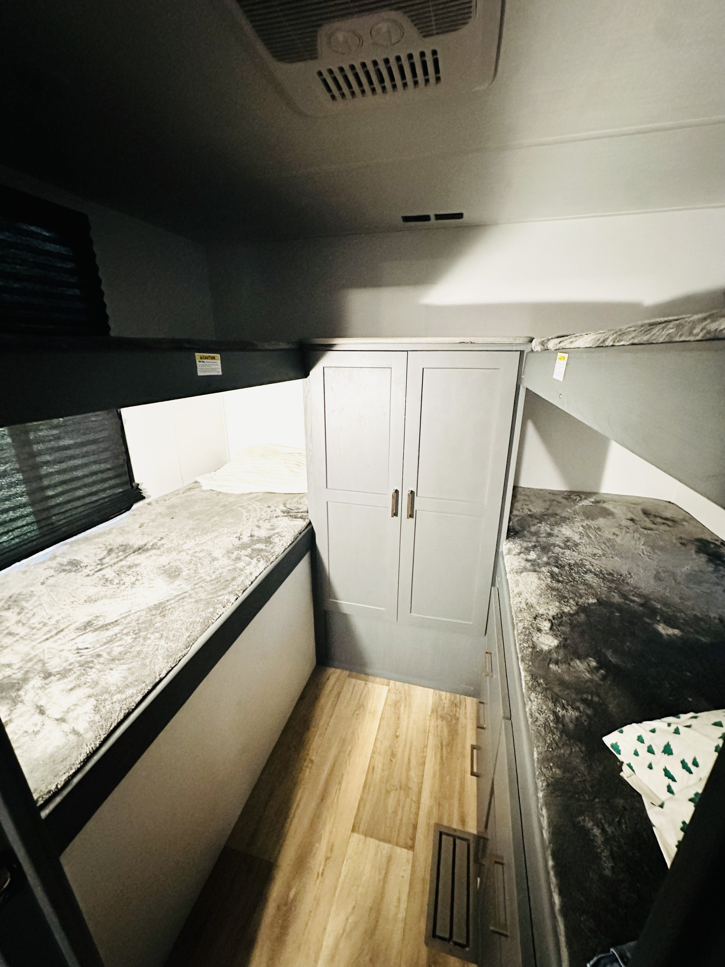 Inside an rv rental: gray bunk beds, central wardrobe, and wood flooring. A compact and functional sleeping space.. Keystone RV Bullet Crossfire 2024