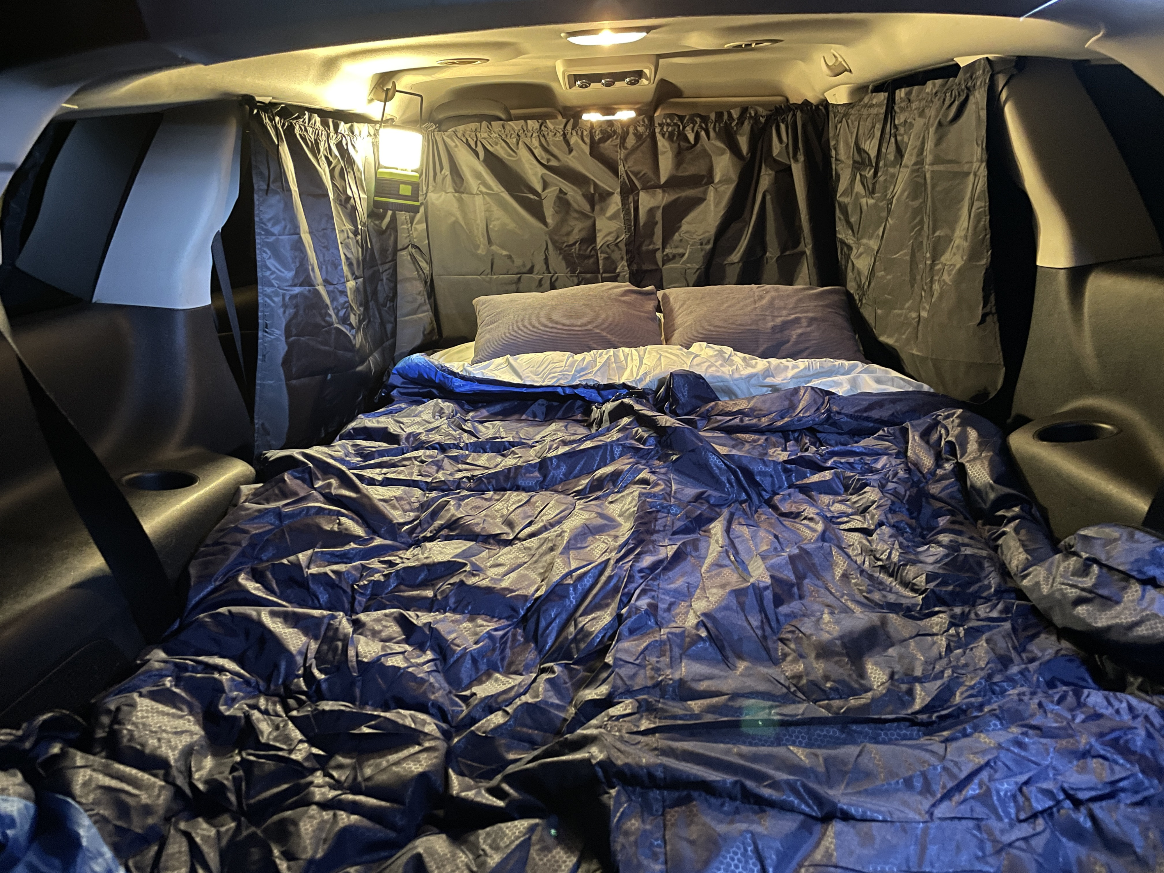 Cozy car camping setup in a vehicle with blackout curtains and bed, creating an RV rental alternative for comfortable sleep.. Dodge Journey 2016