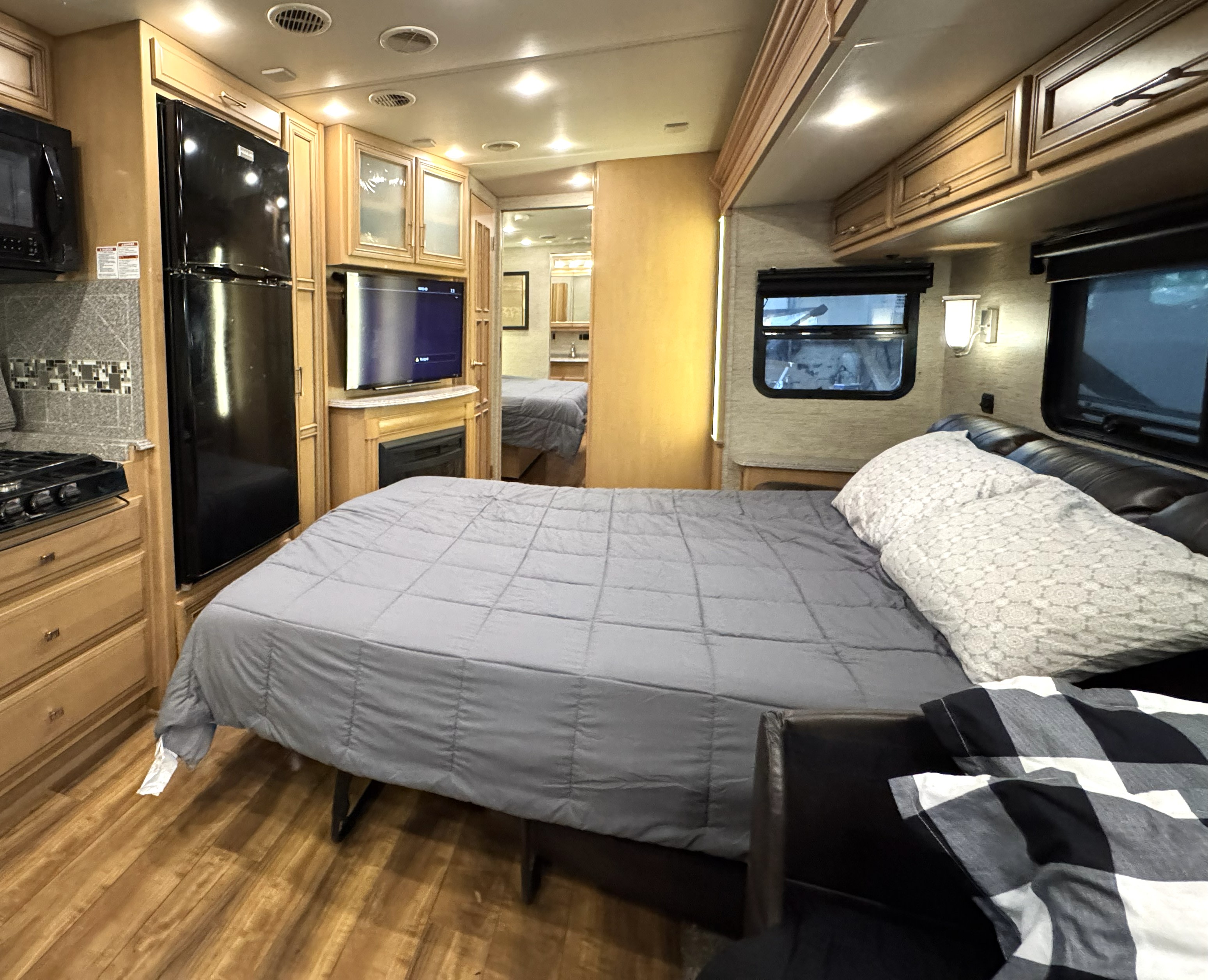 Experience a cozy RV rental interior: bedroom with bed, kitchen with stove/fridge, and lounge area in this spacious motorhome.. Newmar Canyon Star 2016