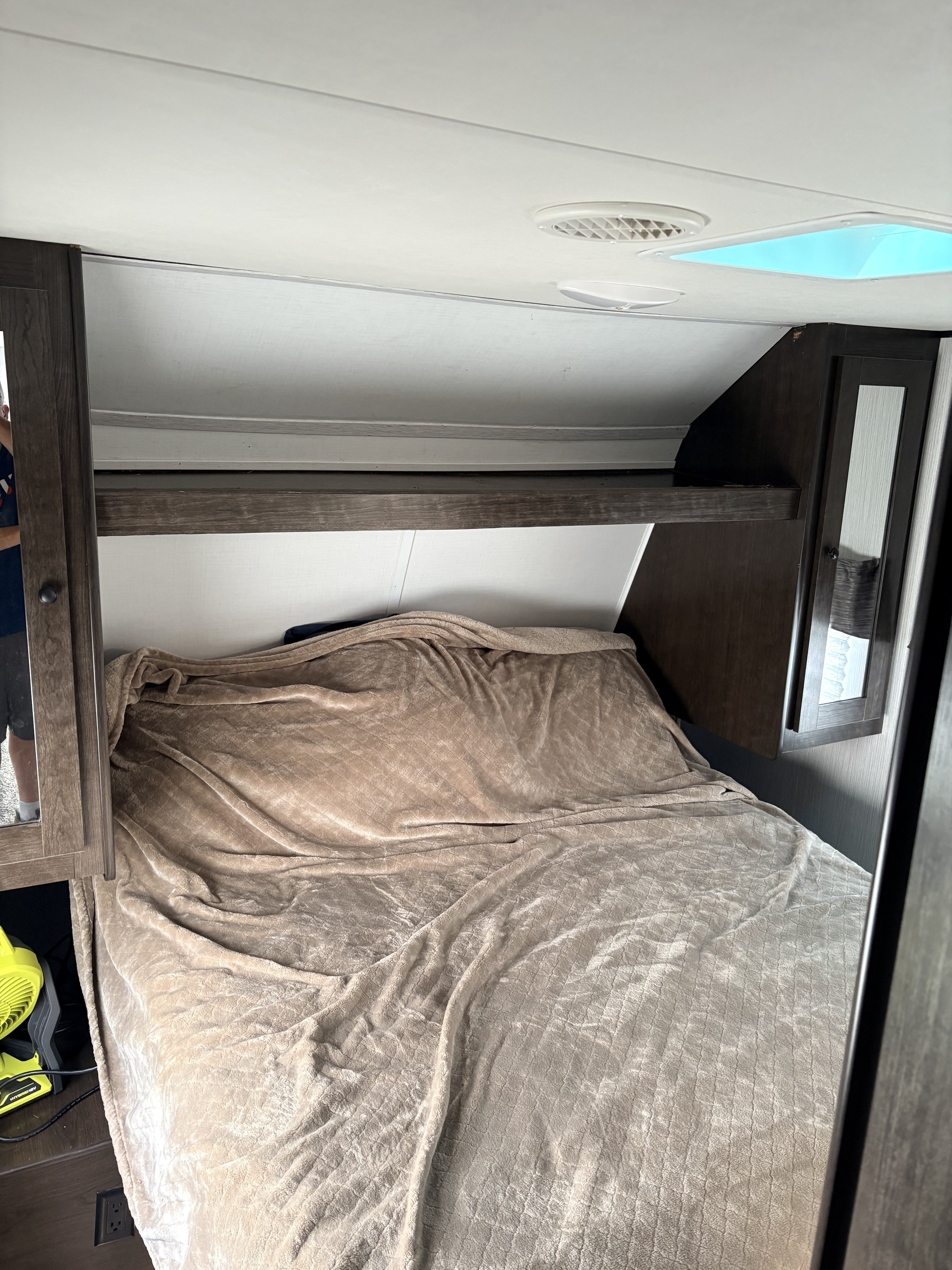 Cozy RV rental bedroom: bed with blanket, overhead shelf, and ceiling with vent and bright skylight.. Heartland RVs Trail Runner 2020
