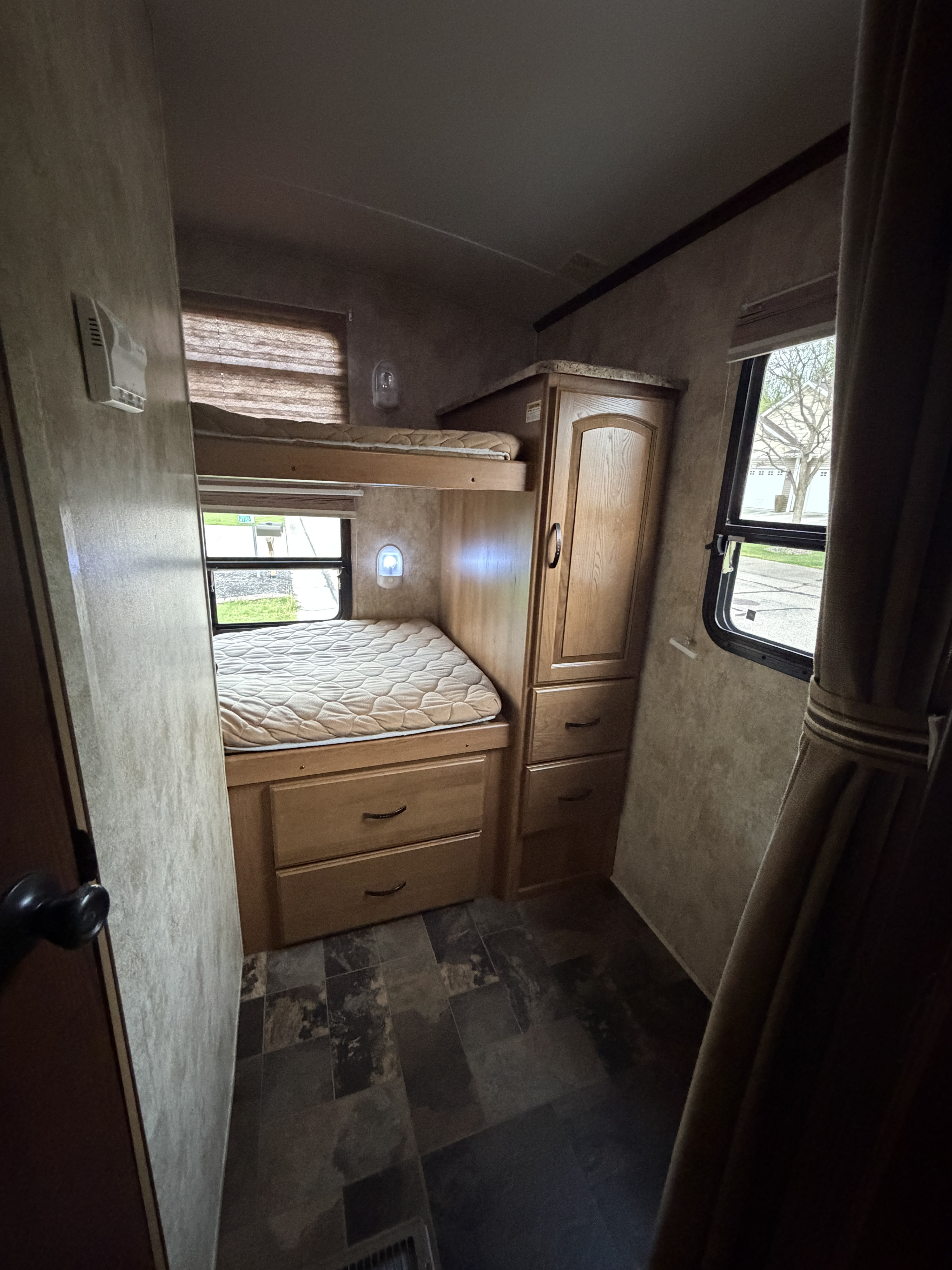 Inside an RV rental bunk room: features compact bunk beds with storage drawers, a wardrobe, and bright windows.. Keystone Outback 2012