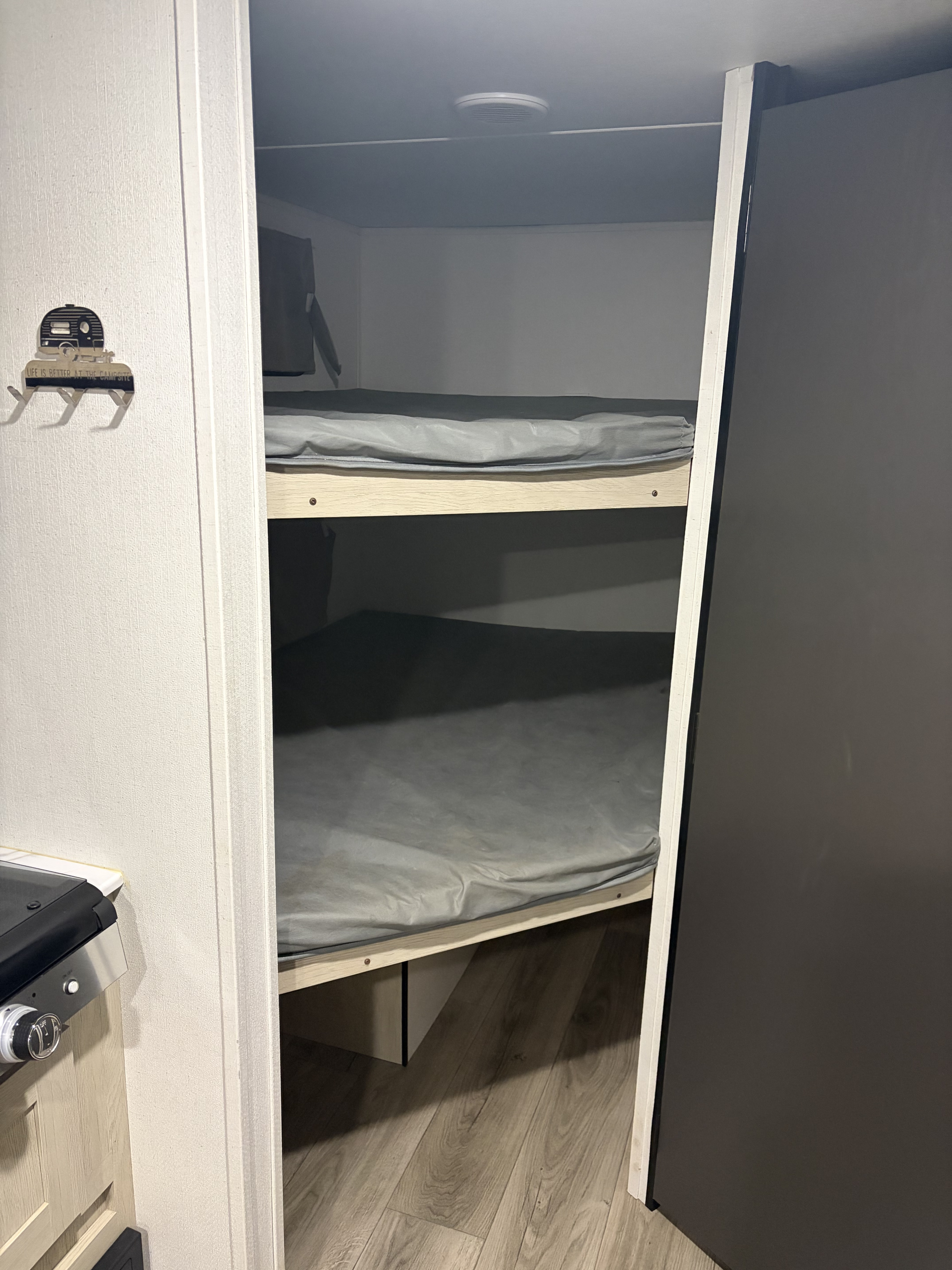 Explore this RV rental's cozy bunk beds, featuring two sleeping spots with grey mattresses, ideal for camping adventures.. Forest River Shasta I-5 2025