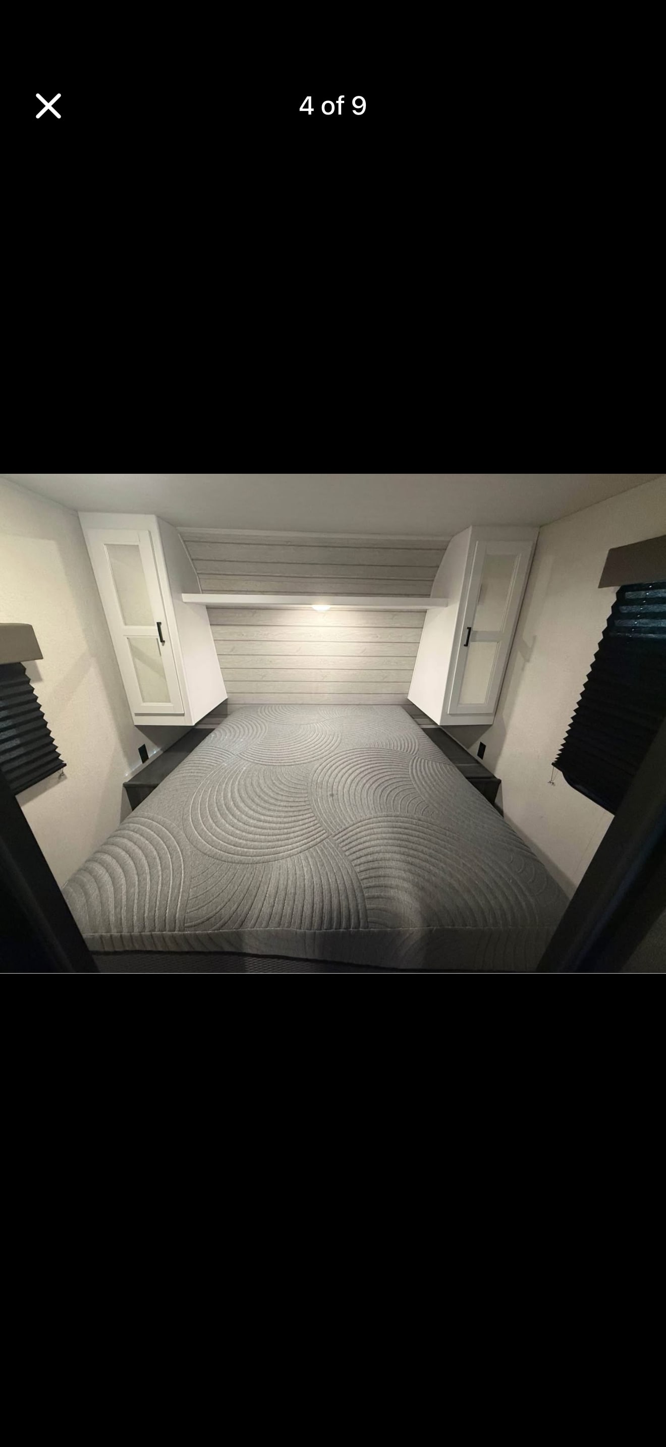 RV rental bedroom: cozy bed with grey quilted cover, modern headboard, overhead cabinets & side blinds for comfort.. Keystone RV Hideout 2022
