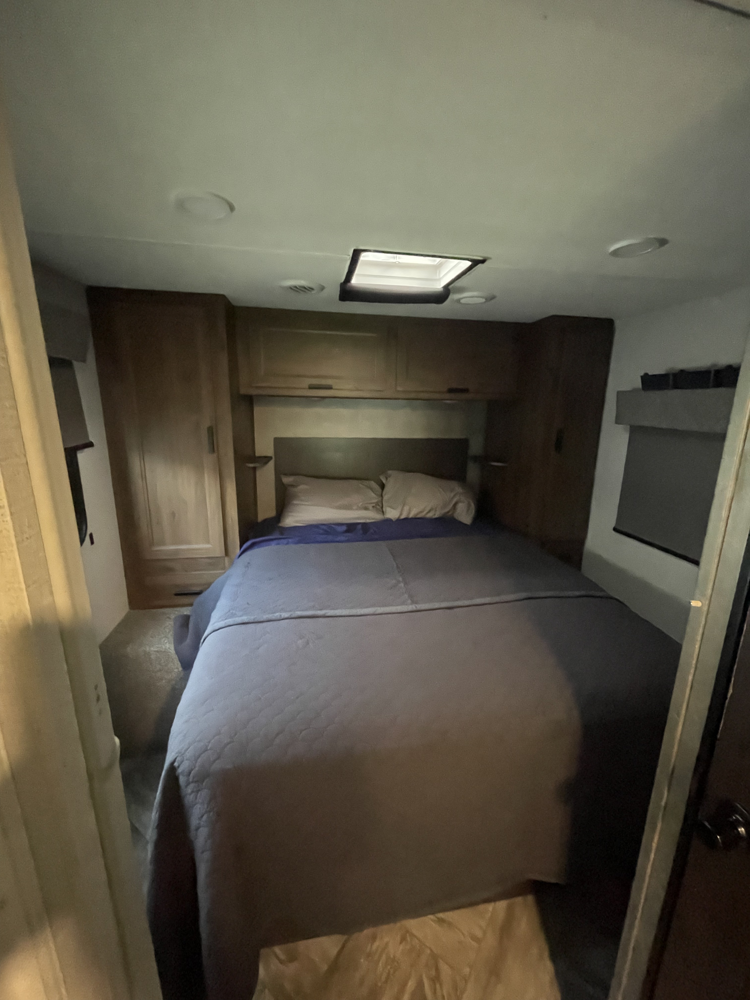 Cozy RV rental bedroom with a comfortable bed, overhead cabinets, and a skylight for natural light.. Forester LE 2022
