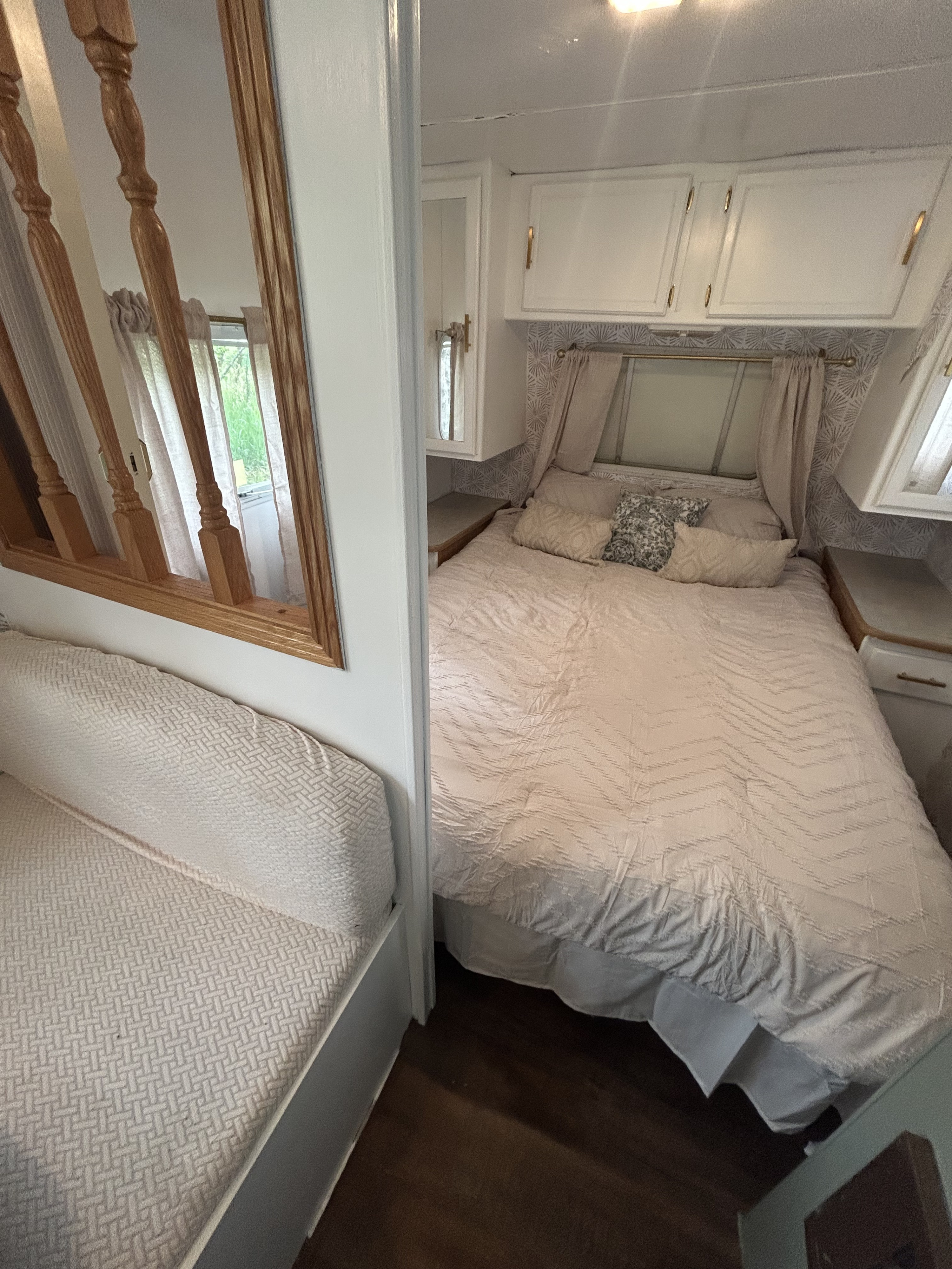 RV rental interior: A cozy bedroom with a comfortable bed, cabinets, and window, adjacent to a patterned sofa/daybed area.. Century-Skyline Century-Skyline Trailer 2003