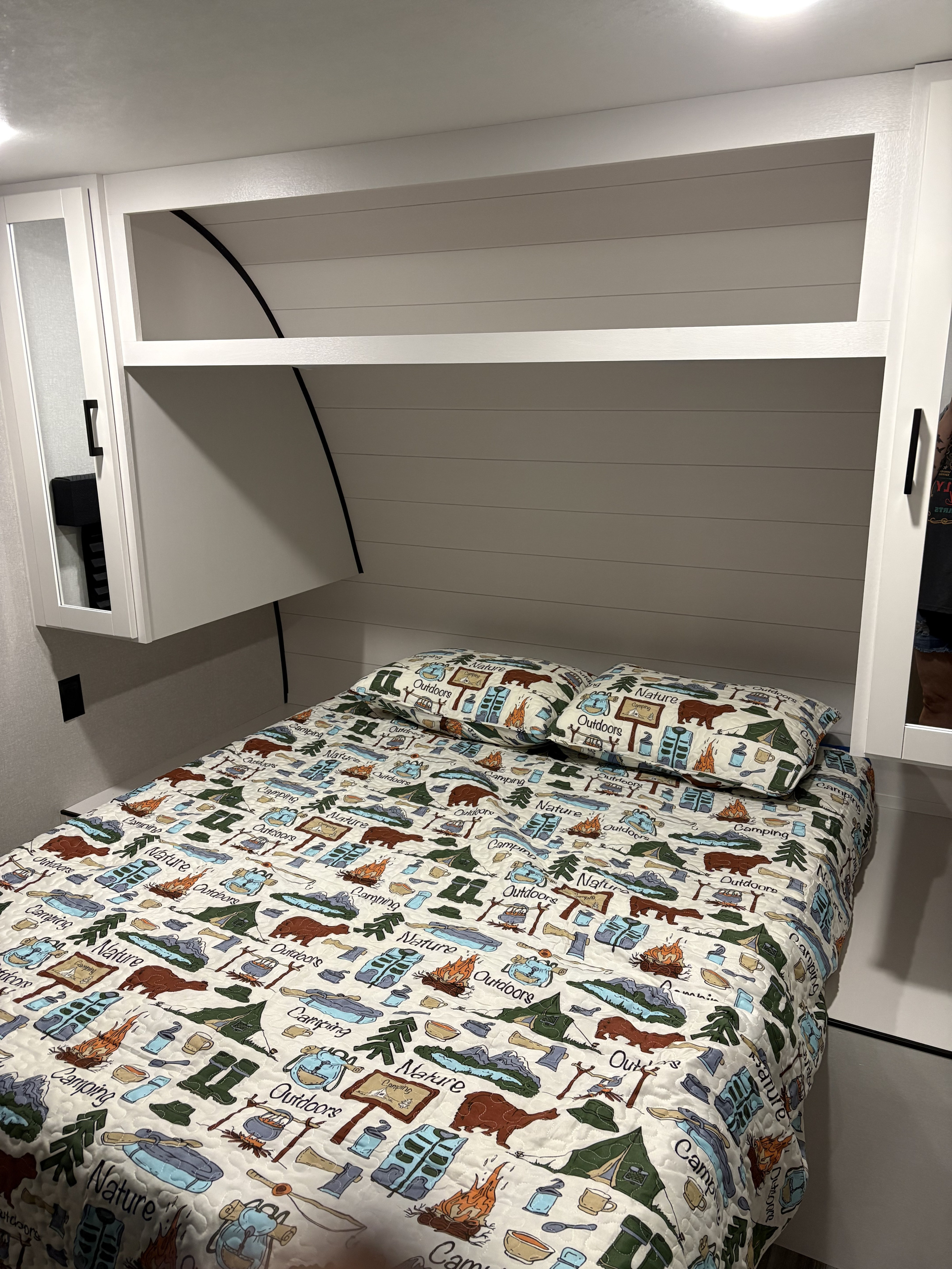 Cozy RV rental bedroom featuring a bed with a fun camping-themed quilt and pillows, complemented by bright overhead storage.. Jayco 2026 Jayco Jay Flight SLX 260BH 2026