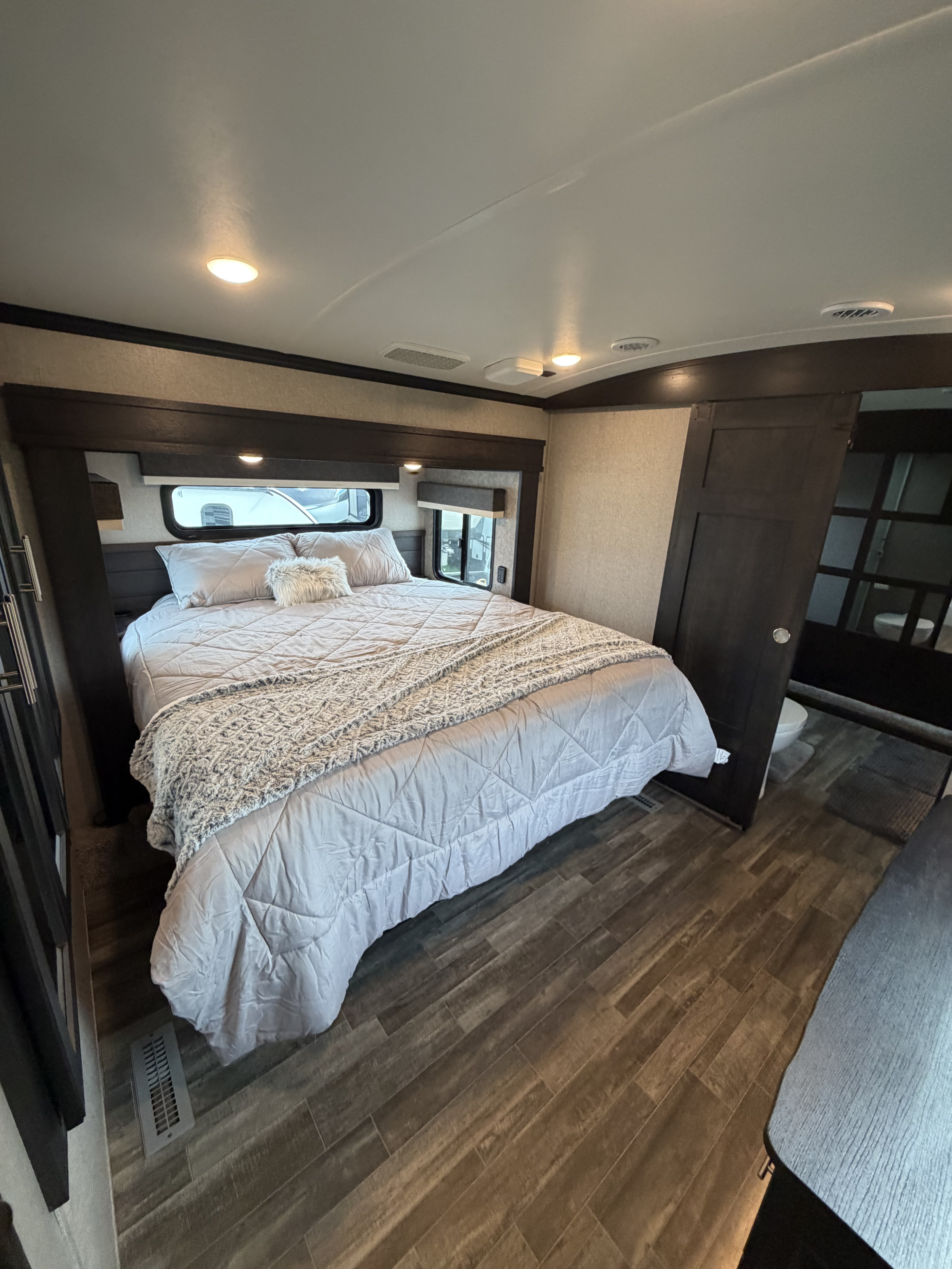 Cozy RV rental bedroom with a large bed, modern decor, and an ensuite bathroom peeking through the sliding door.. Jayco North Point 2021