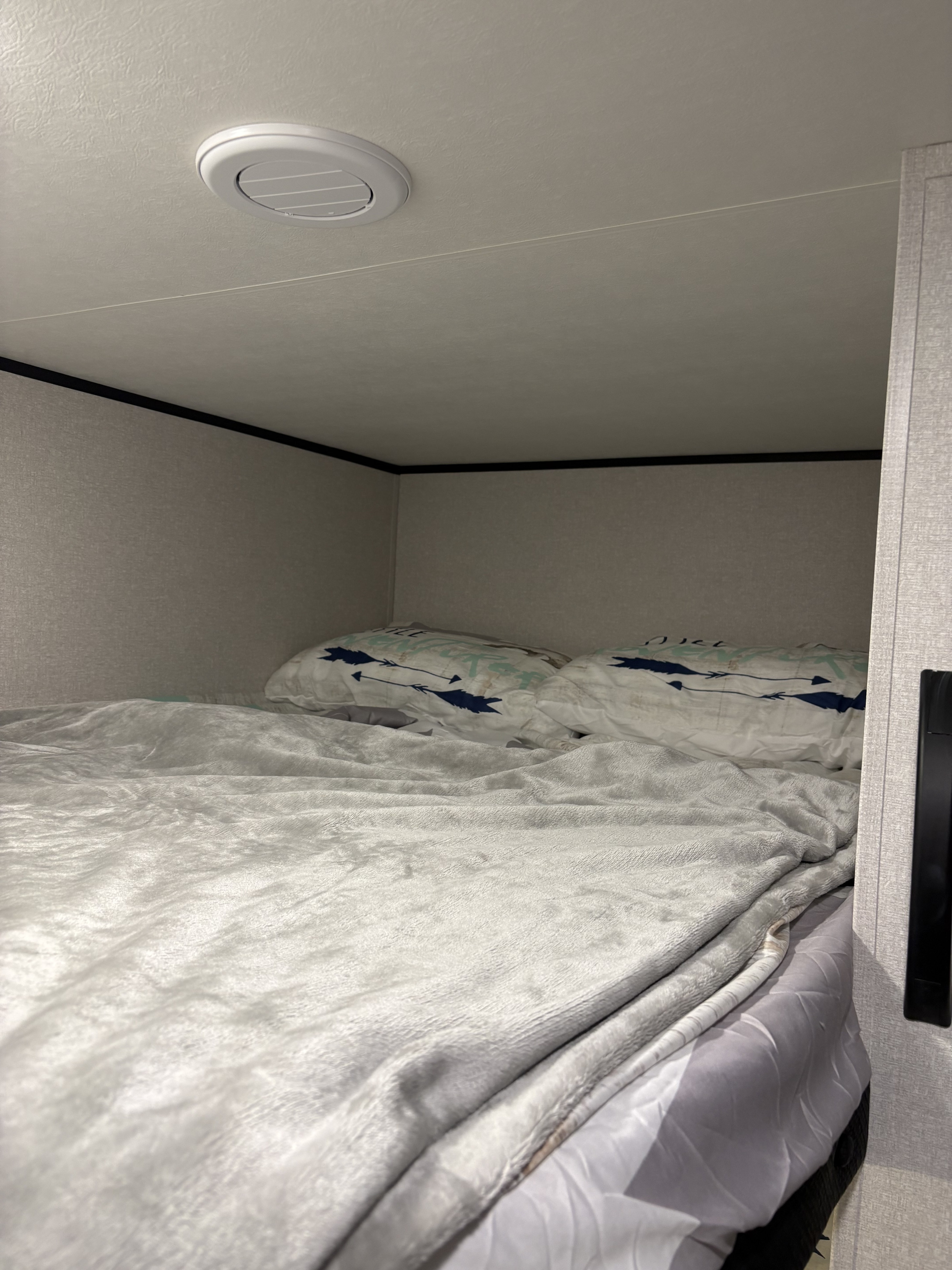 Cozy bunk bed inside an RV rental, featuring soft grey bedding, patterned pillows, and a ceiling vent for air.. Jayco 2026 Jayco Jay Flight SLX 260BH 2026