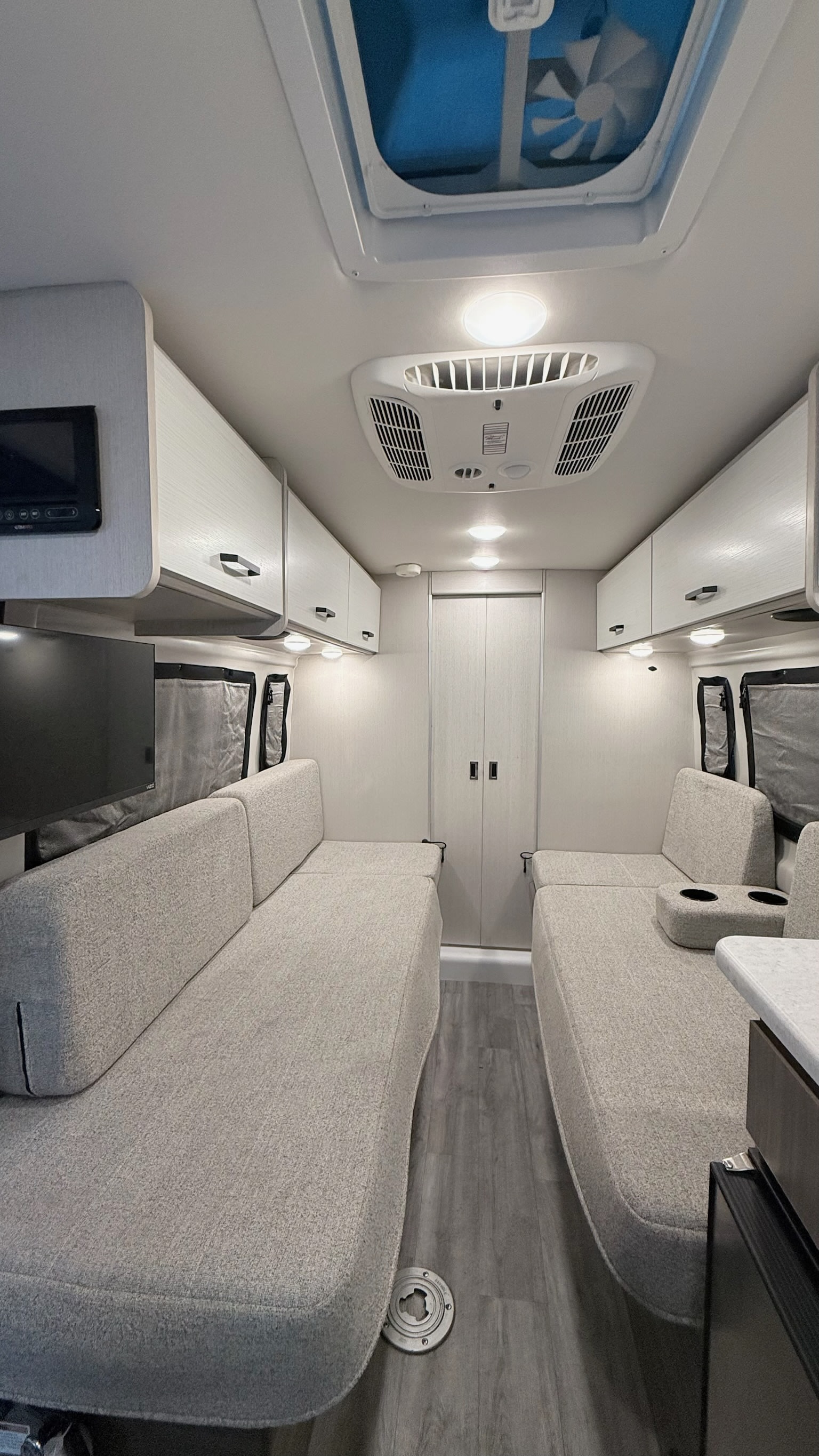 Bright, modern rv rental interior with convertible living/sleeping benches, overhead cabinets, AC, and ceiling fan.. Thor Dazzle 2024