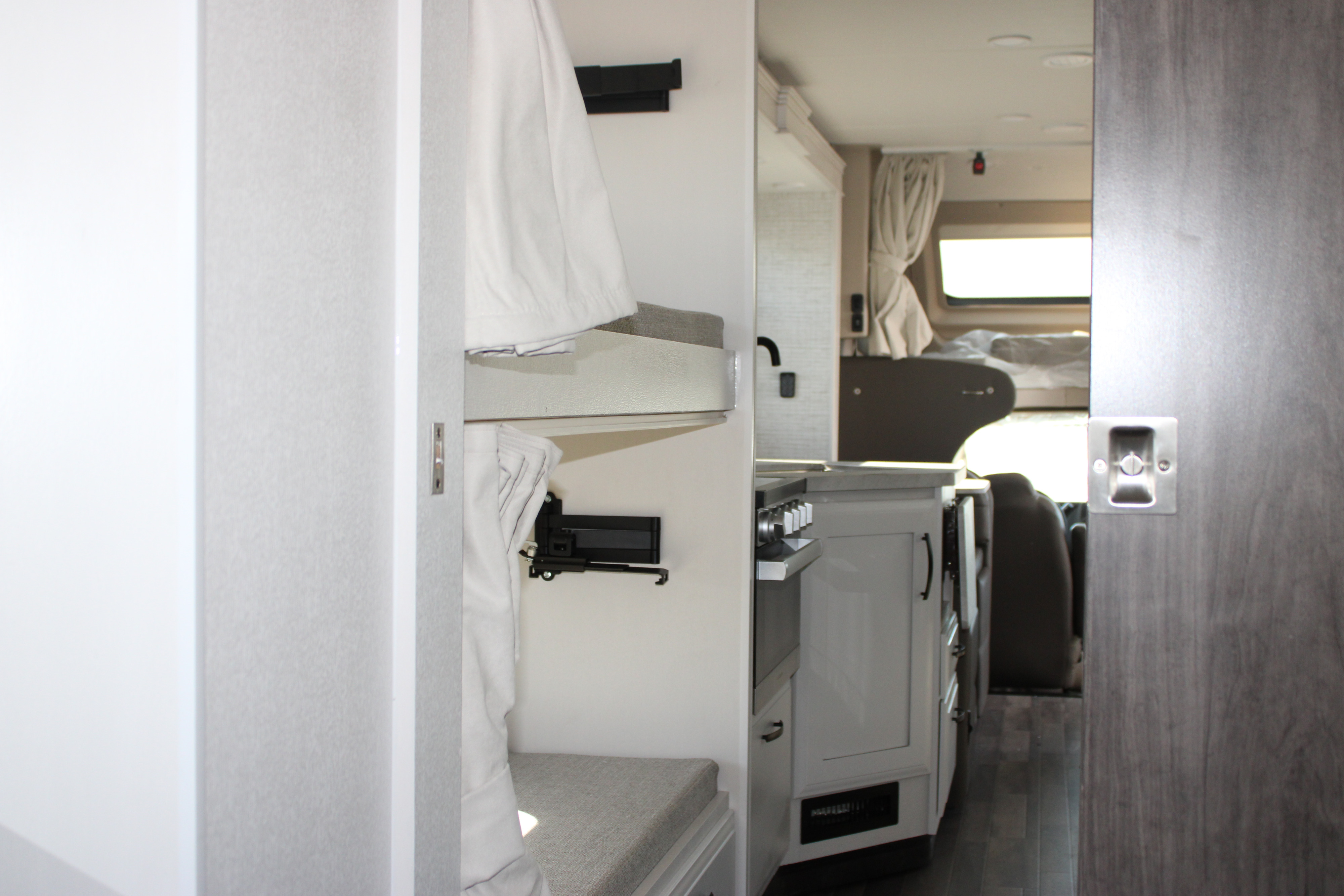 View inside an RV rental, showing cozy bunk beds, a functional kitchen with a stove, and the front cabin area.. Jayco Greyhawk 2025
