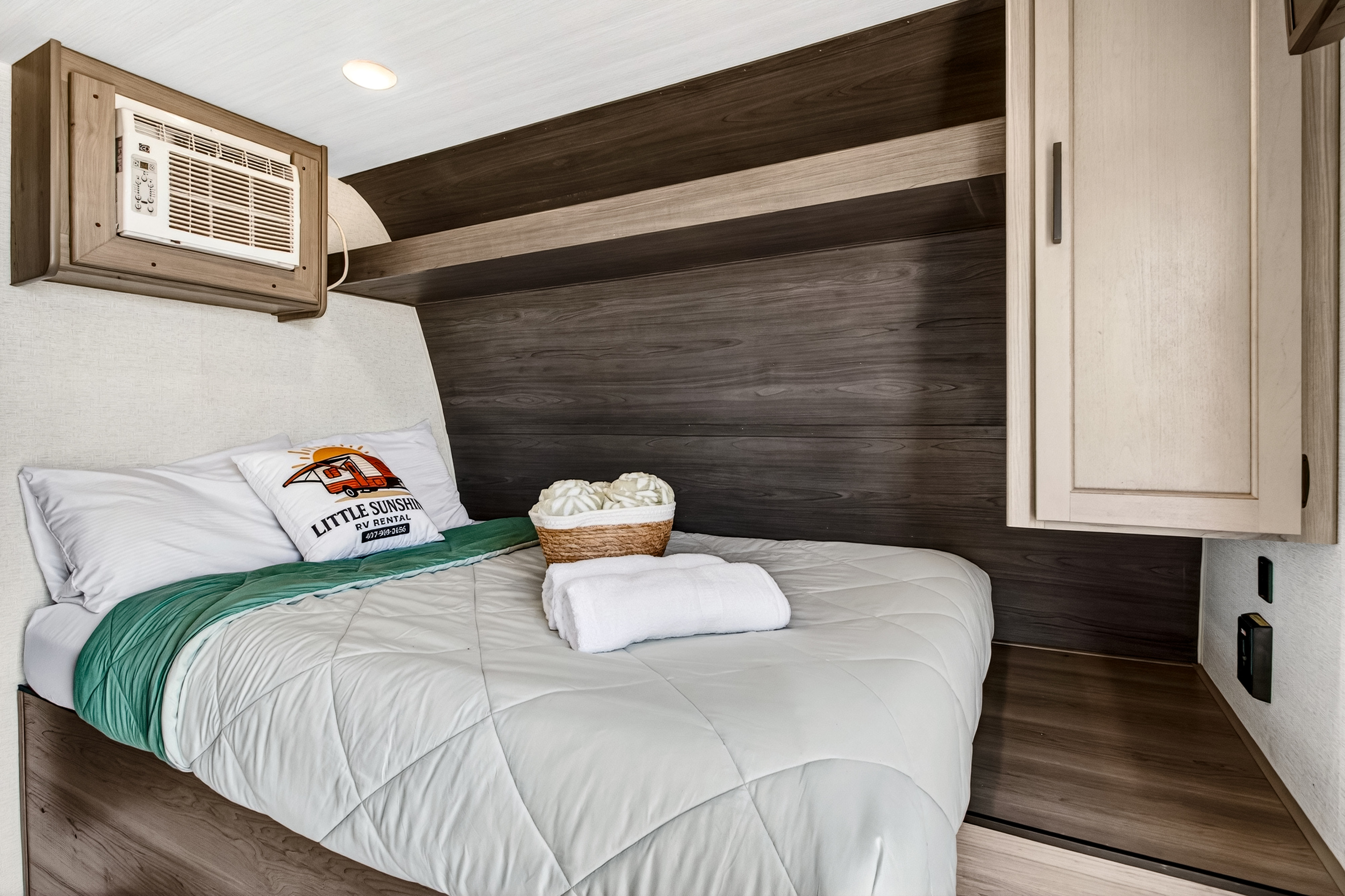 Inside a Little Sunshine RV rental: a comfy bedroom with AC, storage, and fresh linens, perfect for a cozy escape.. Keystone RV Hideout Sport 2024