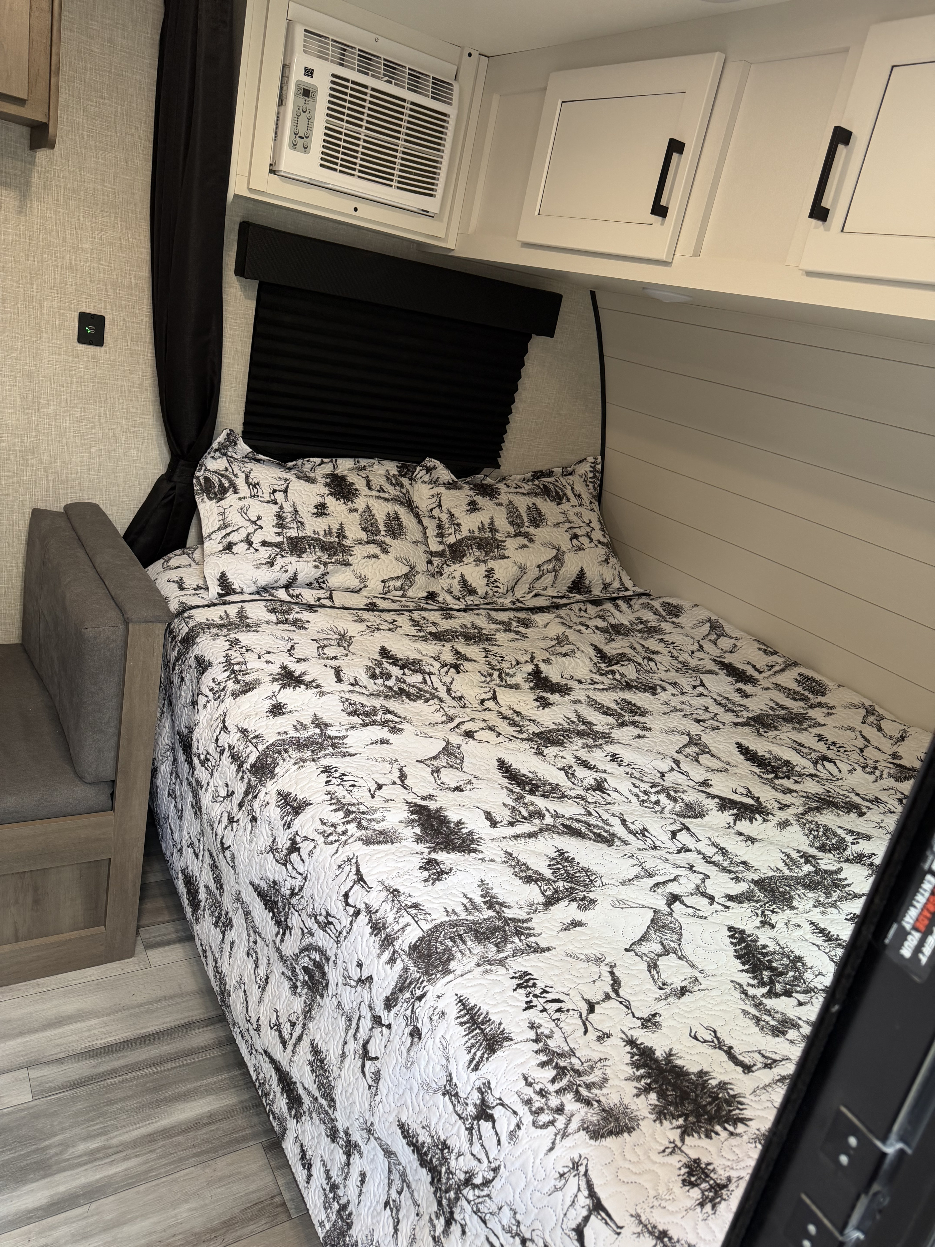 Cozy RV rental bedroom with patterned bed, built-in AC, cabinets, and a convenient wall-mounted charging port.. Jayco Jay Flight SLX 2024