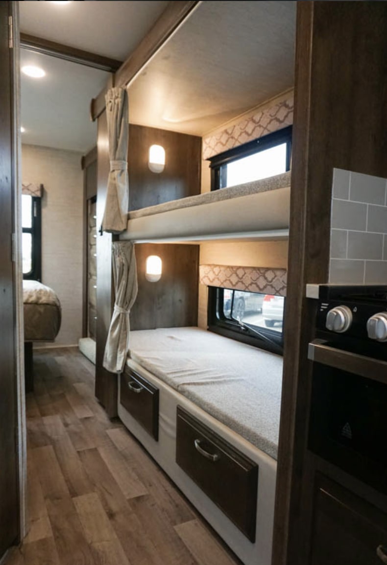 Step inside this RV rental! Features include cozy bunk beds with windows, privacy curtains, and a compact kitchen area.. Jayco Redhawk 2020