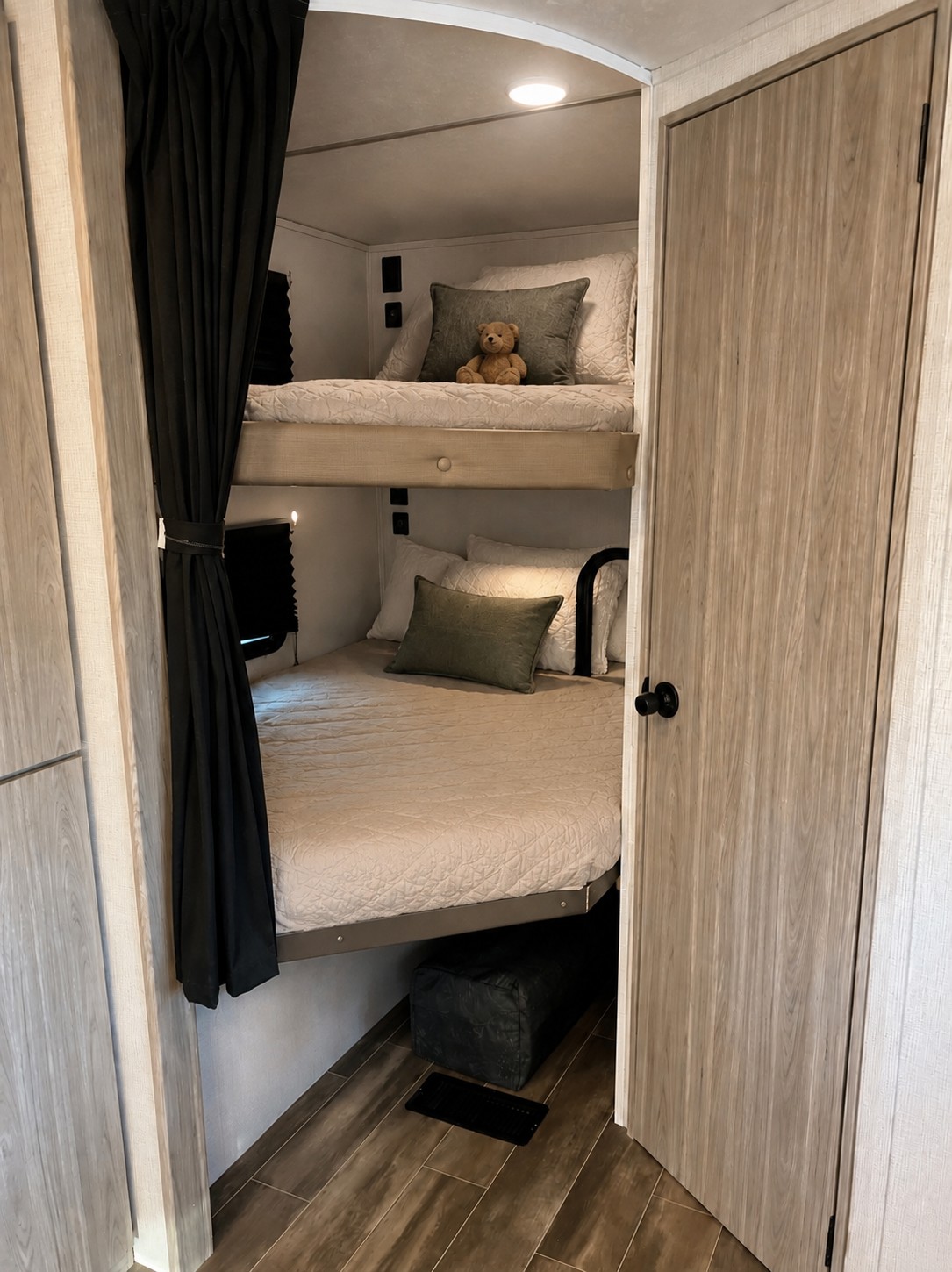 Cozy RV rental sleeping area: stacked bunk beds with plush bedding, decorative pillows, and a teddy bear on the top bunk.. Keystone RV Passport SL 2022