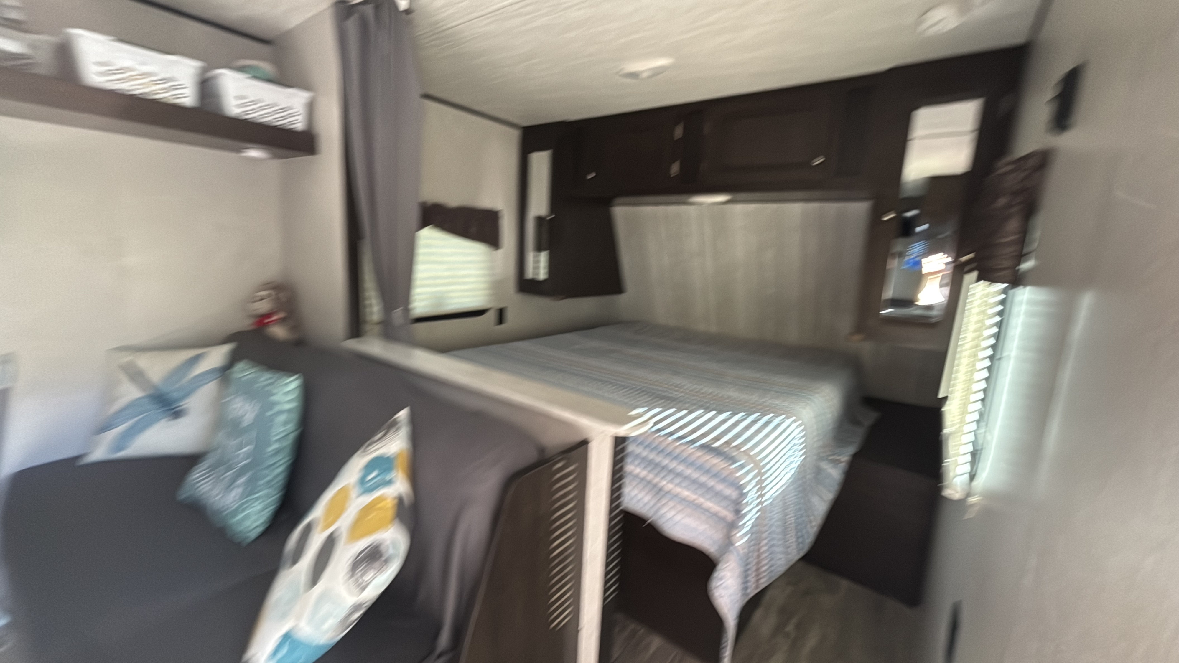 RV rental interior showcasing a cozy bed & sofa area with storage shelves, perfect for travel comfort.. Heartland RVs Pioneer 2021