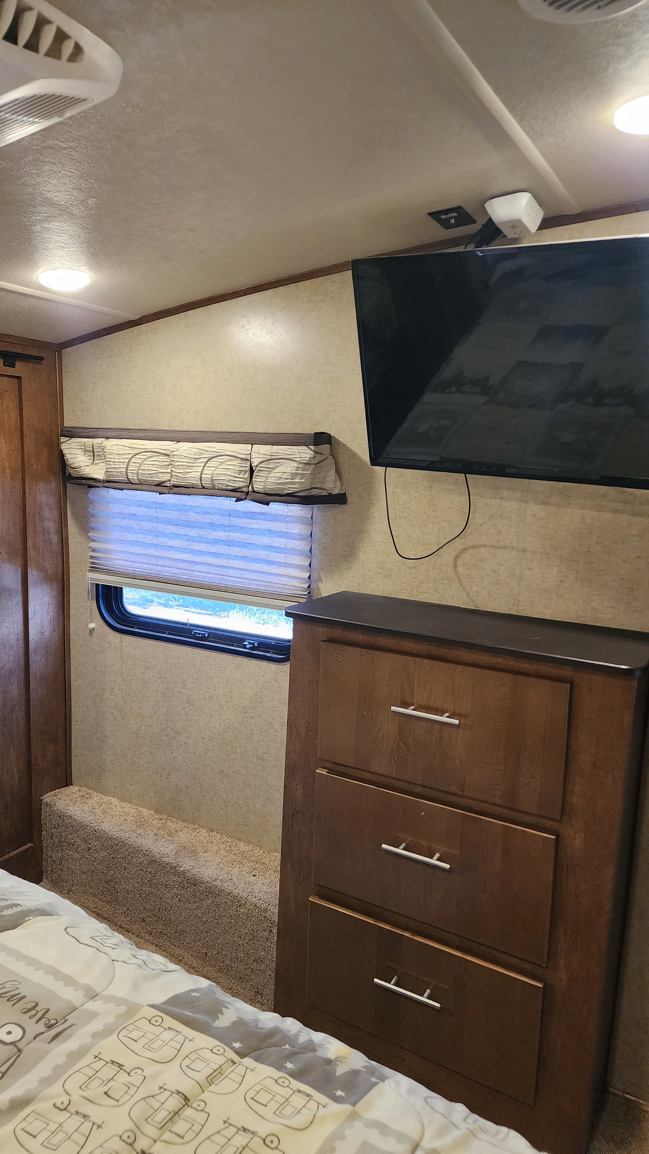 Inside an RV rental bedroom: TV, dresser, window with blinds, and bed. A cozy and compact sleeping area for travelers.. Forest River Sabre 2018