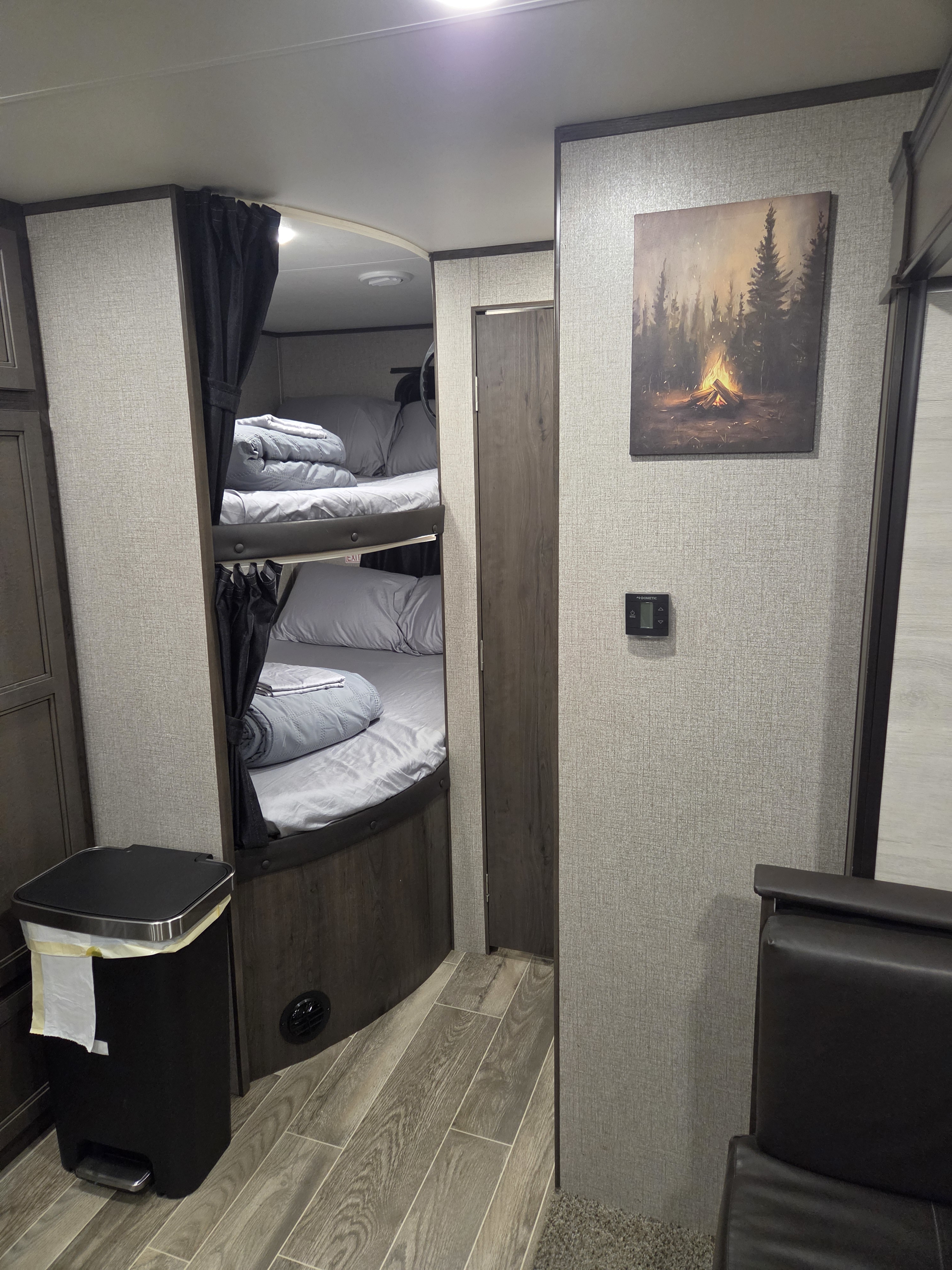 Rv rental interior showing comfy bunk beds, wall art with a campfire, and a Dometic thermostat. Ready for your next camping adventure.. Jayco Jay Flight SLX 2021